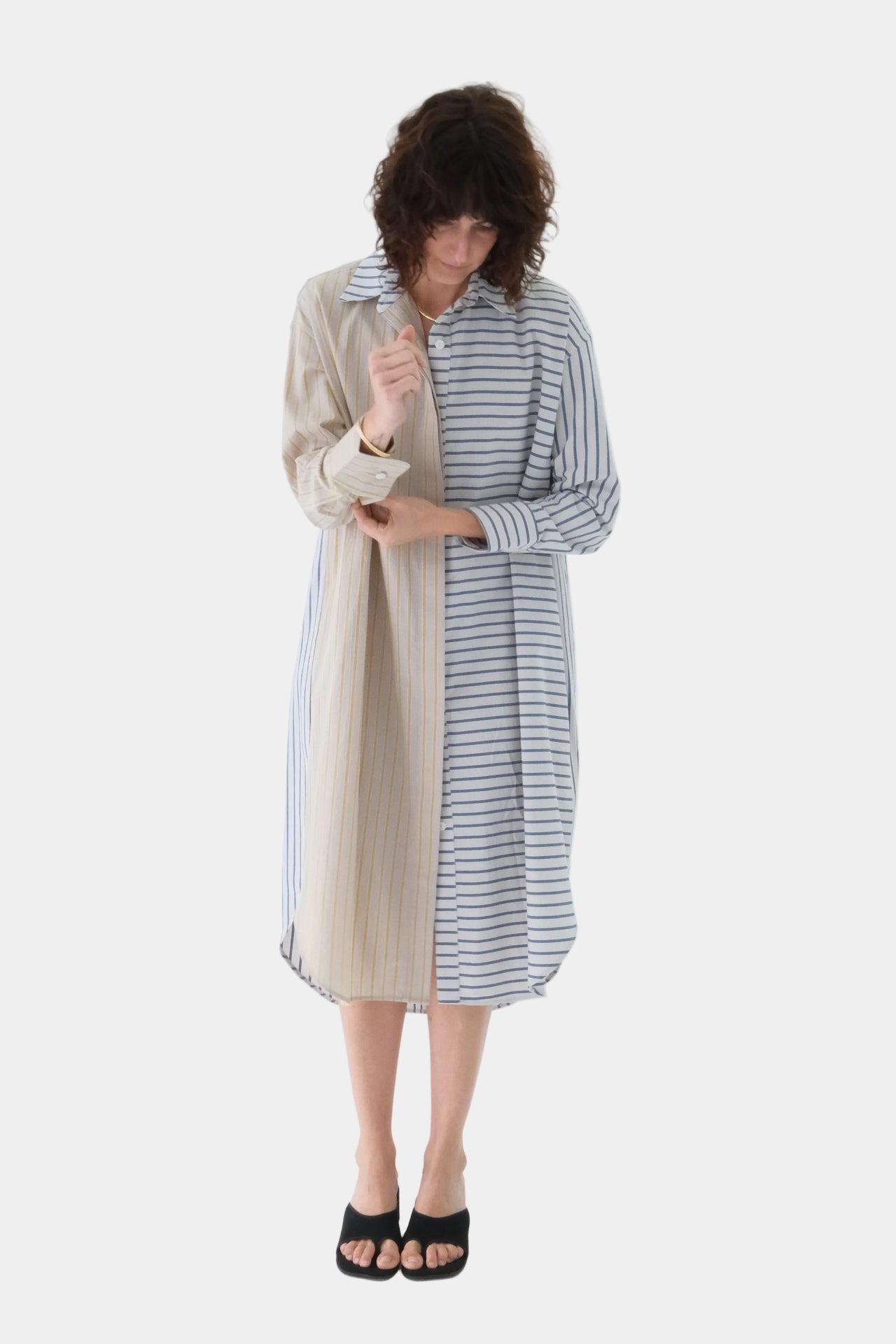 Woman wearing a two-tone dress with beige and striped patterns on a white background