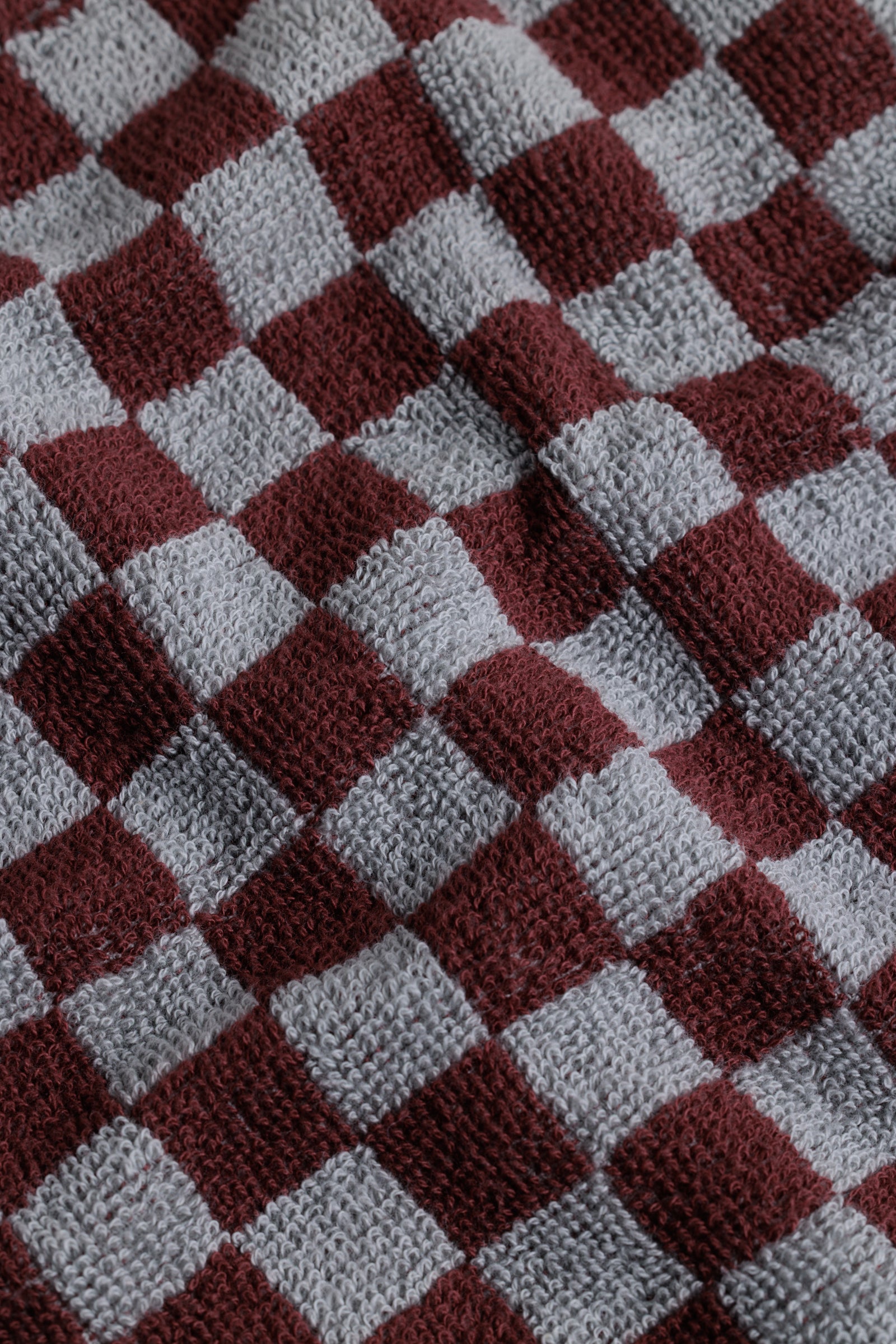 Close-up of a checkered fabric pattern with burgundy and grey squares.