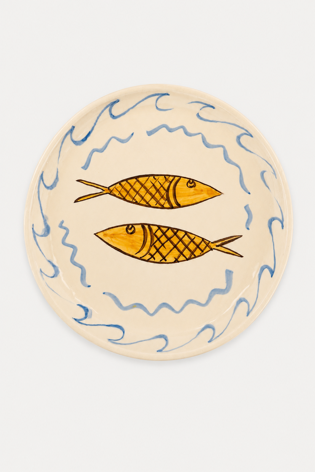 A Di Lunedi sardine plate with a cream-colored glaze, decorated with two yellow-orange fish and blue wavy lines, shown on a clean white background - East Coast General