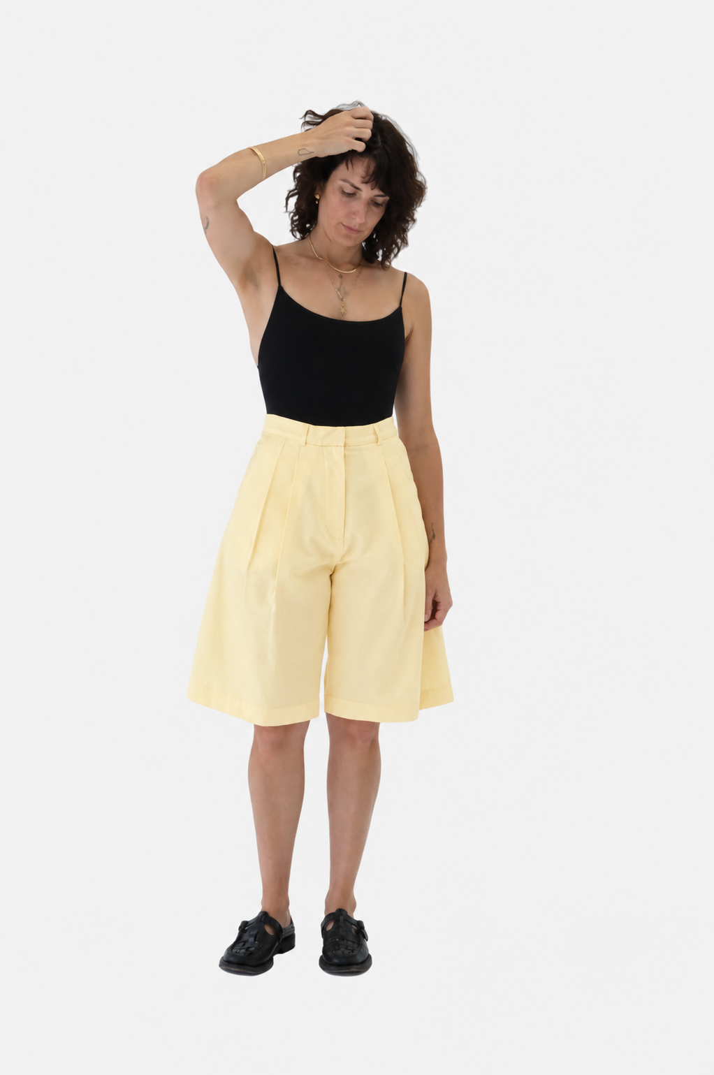 A lady wearing the lido Trentasei in black and ECG No.34 shorts in butter, viewed from the front - East Coast General