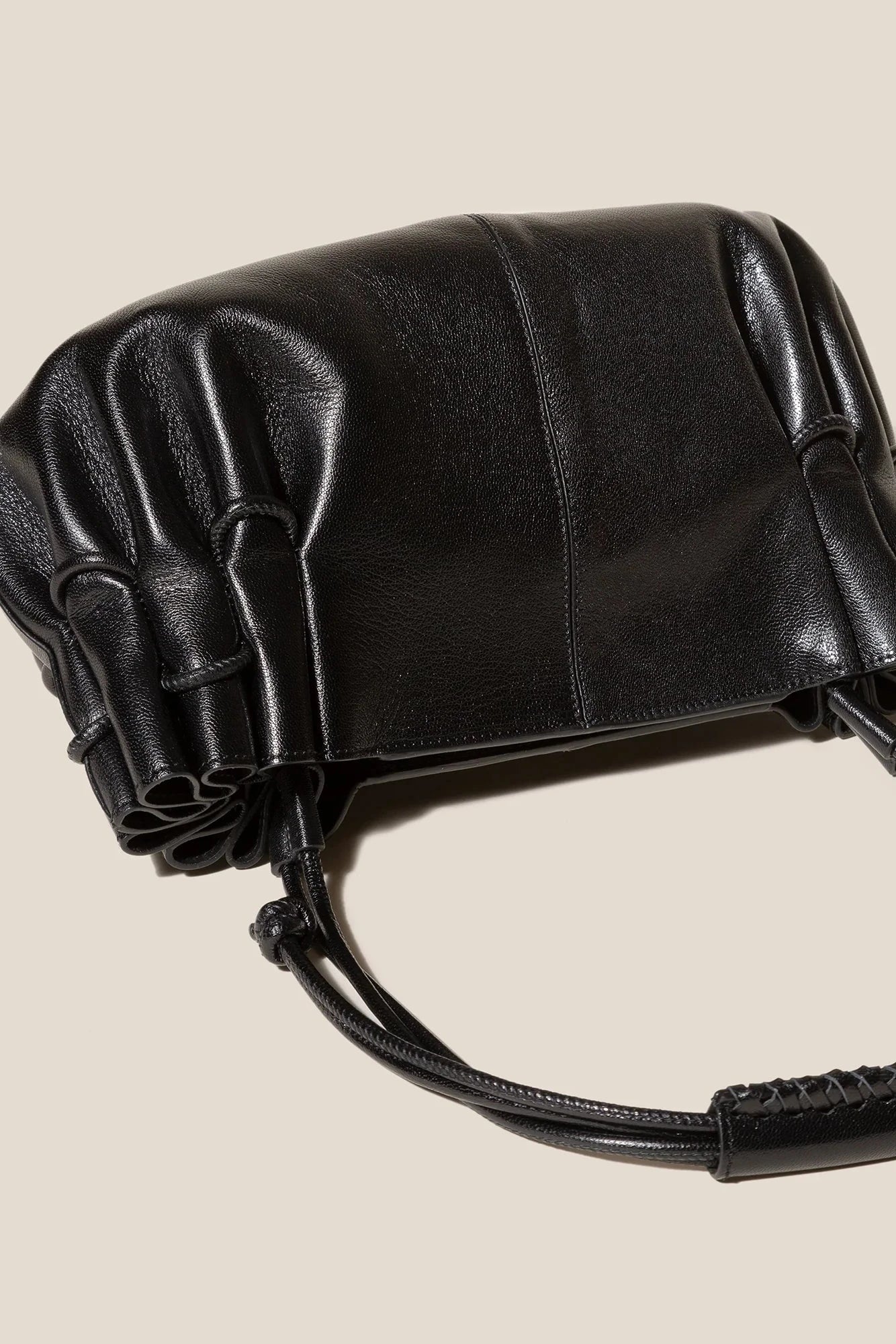 Black leather handbag with drawstring on a beige background