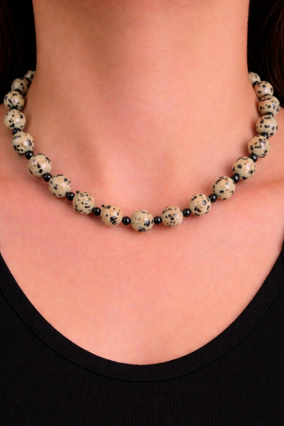 Necklace with black and white beads worn by a person against a black background