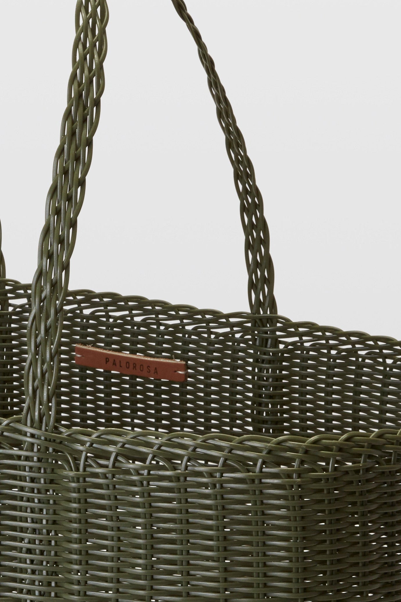 Woven basket with handles and a visible brand label on a light gray background