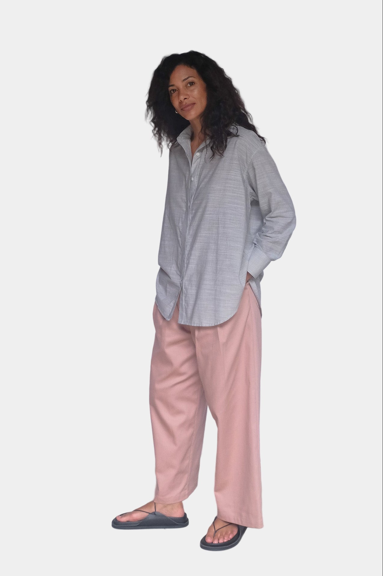 Person wearing a light gray shirt and pink pants against a white background