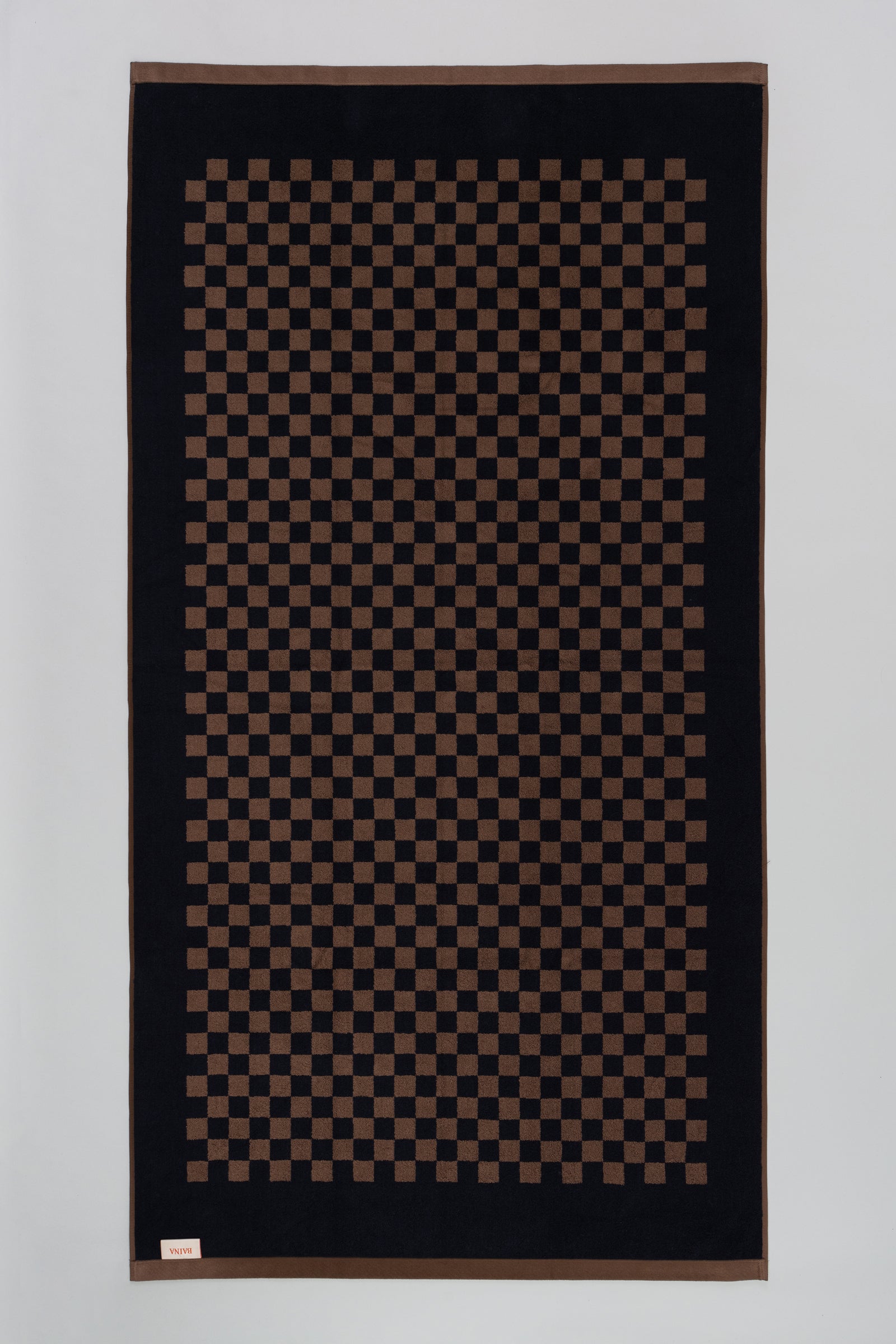 Checkered patterned rpool towel with brown and black colors on a plain background