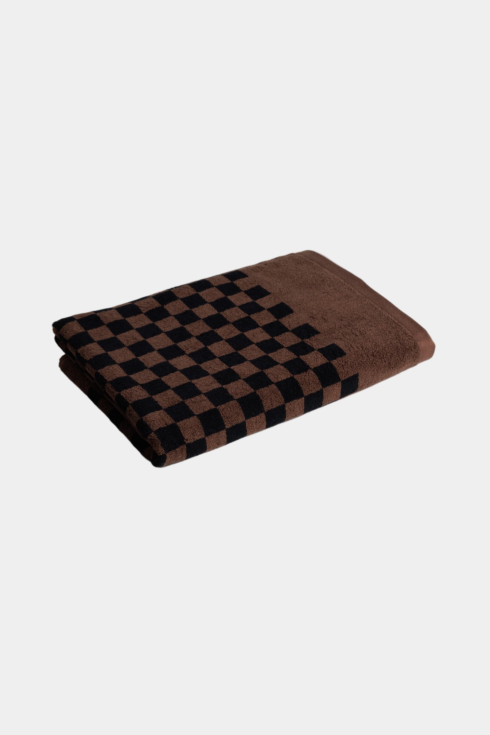 Folded brown and black checkered pool towel on a light gray background