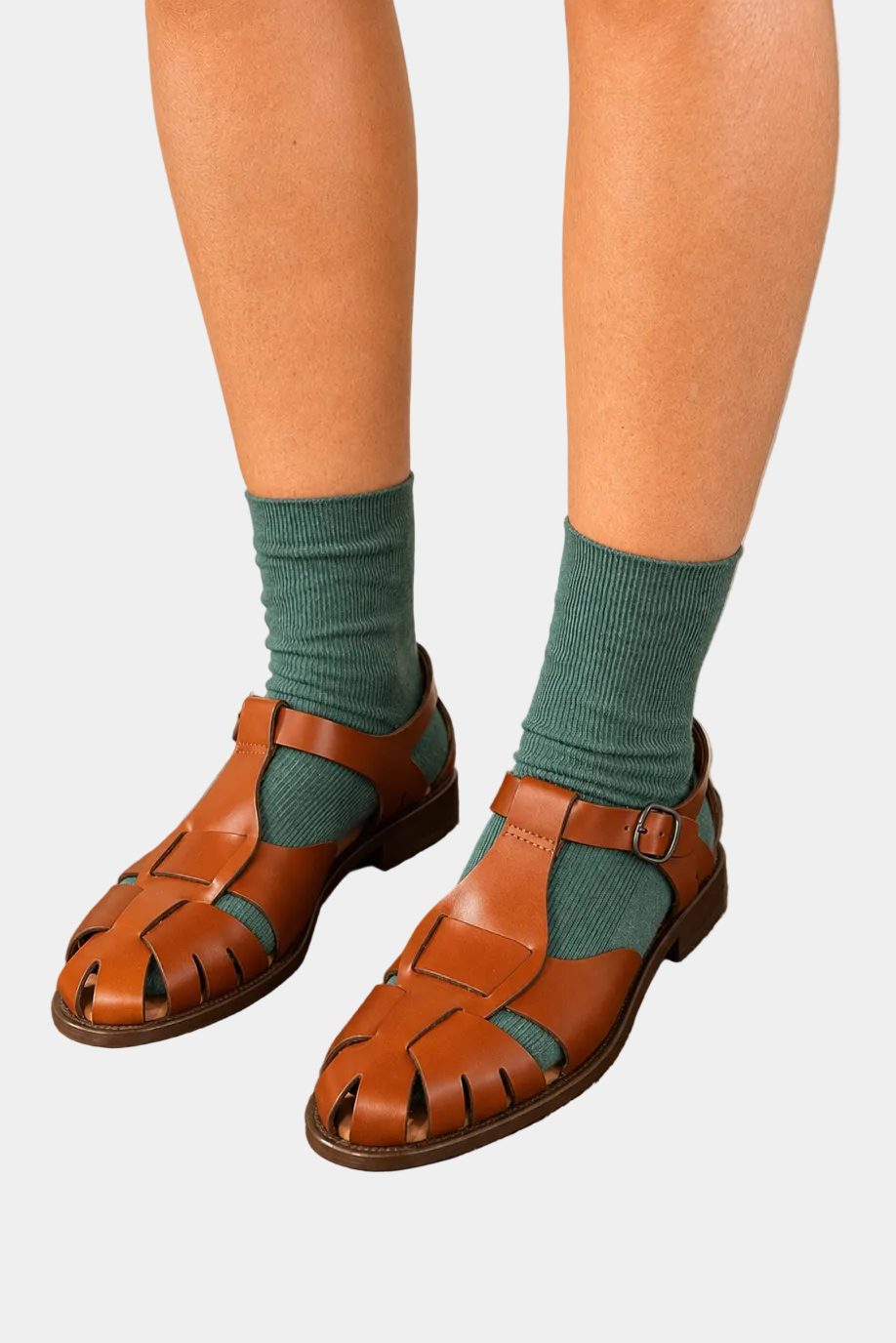 Person wearing brown sandals and green socks against a plain background