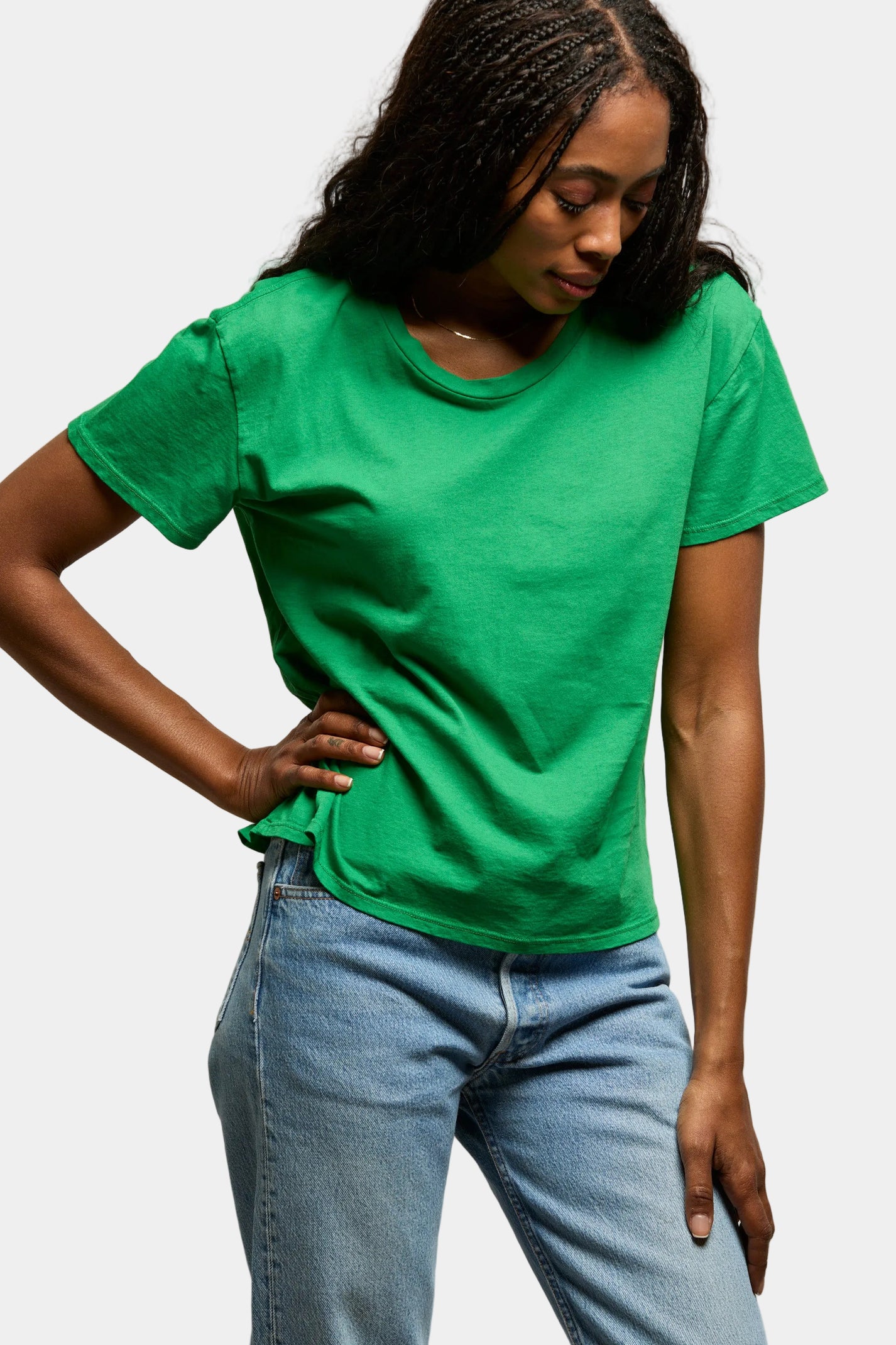 Person wearing a green t-shirt and blue jeans against a plain background