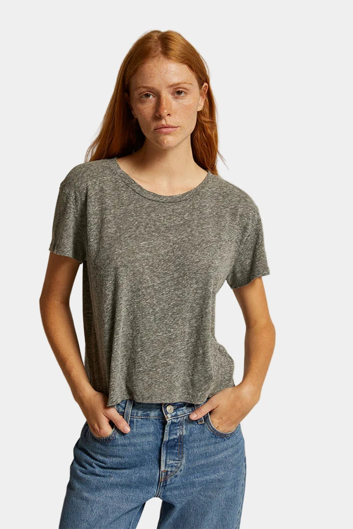 Woman wearing a gray t-shirt and blue jeans against a plain background