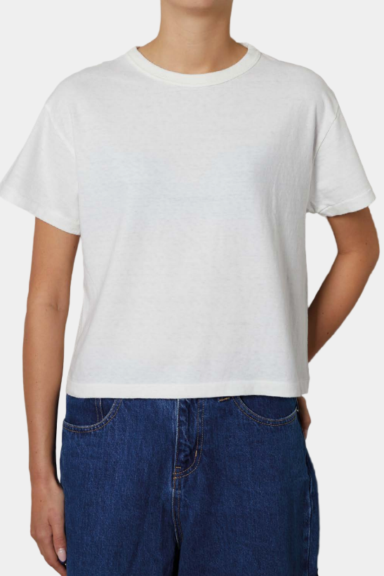 women wearing a white cropped tee and blue jeans against a white background