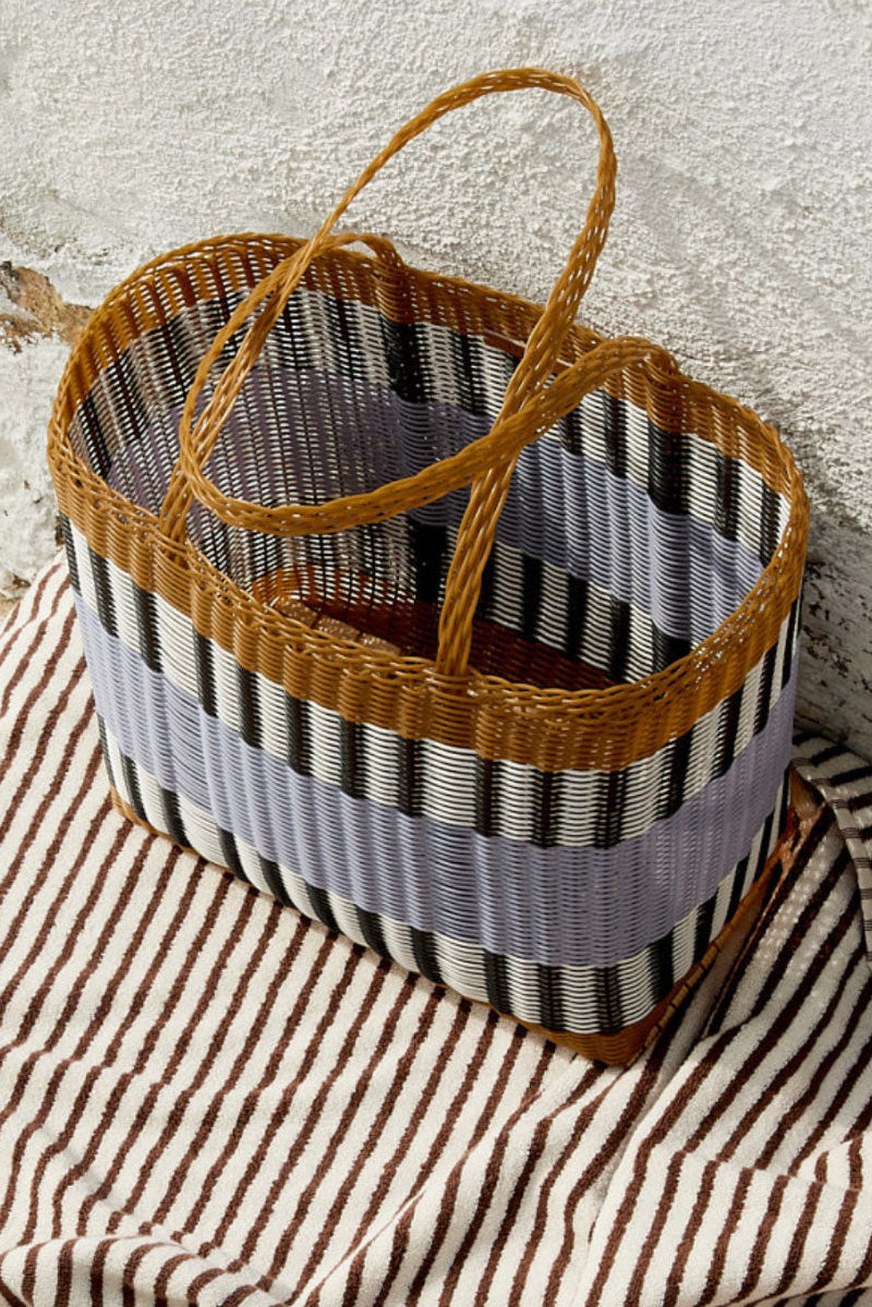 Woven basket with striped pattern on a textured surface