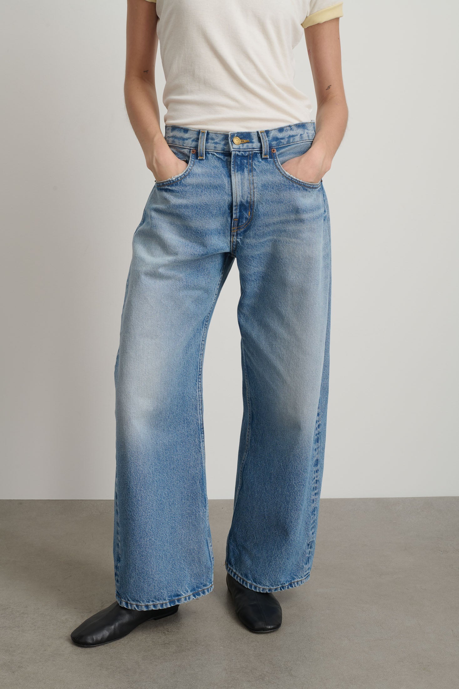 Person wearing blue jeans with a plain background
