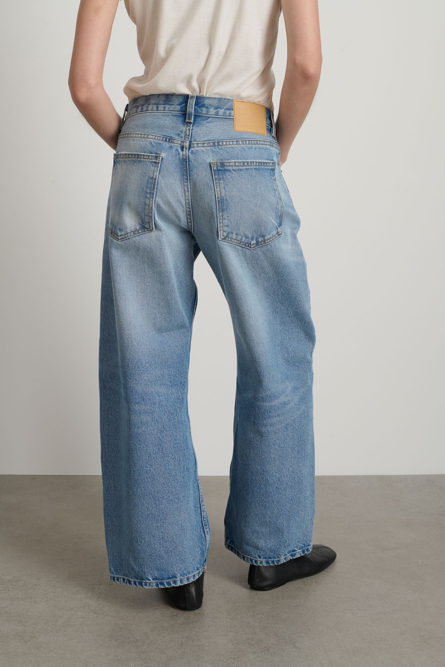 Person wearing light blue jeans with a plain background