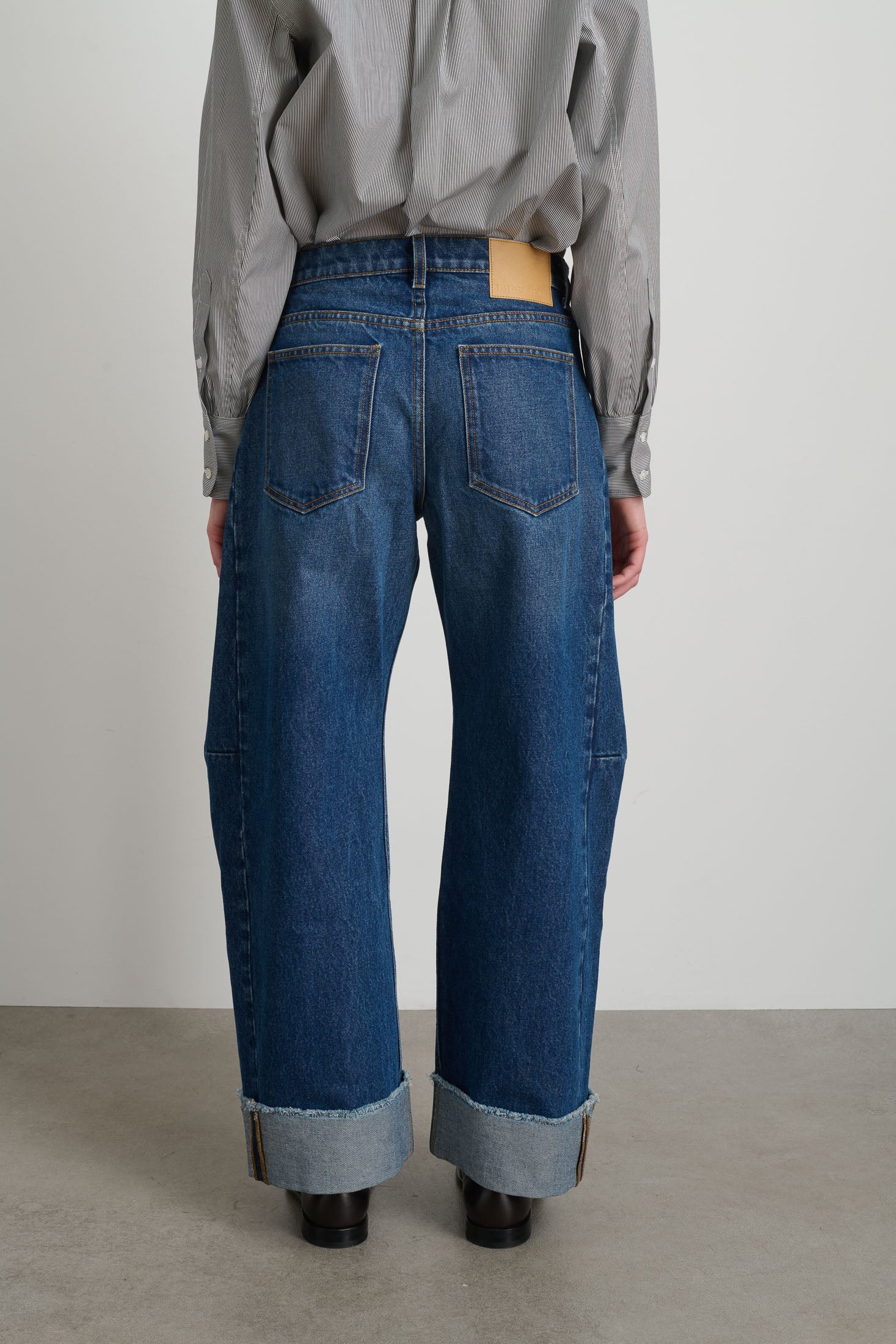 Person wearing blue jeans with a plain background