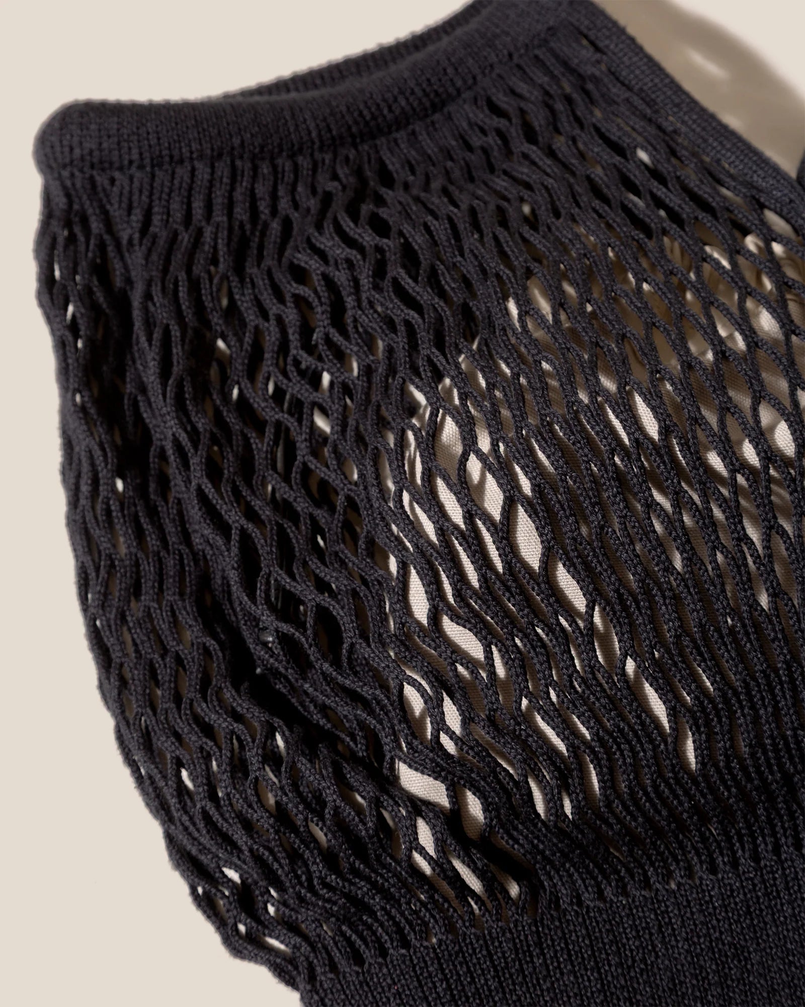 Close-up of a black crochet bag on a beige background