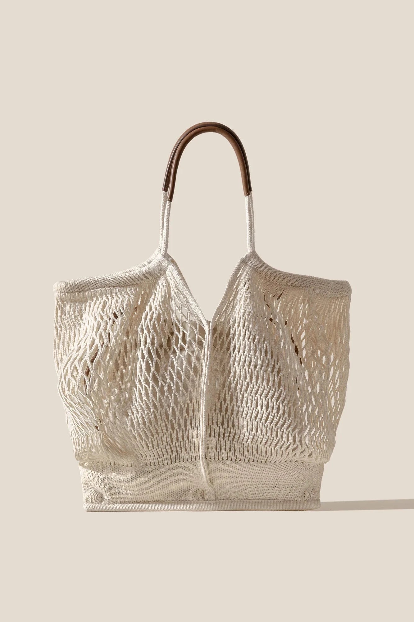 Netted tote bag with leather handle on a beige background