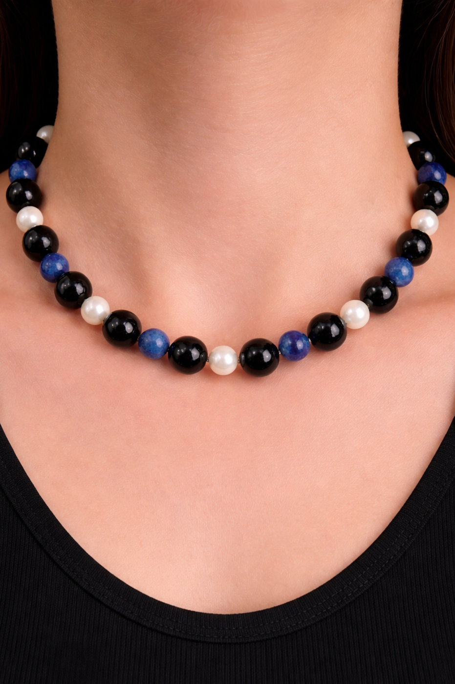 Necklace with black onyx , blue lapis, and freshwater pearls on a person wearing a black top.