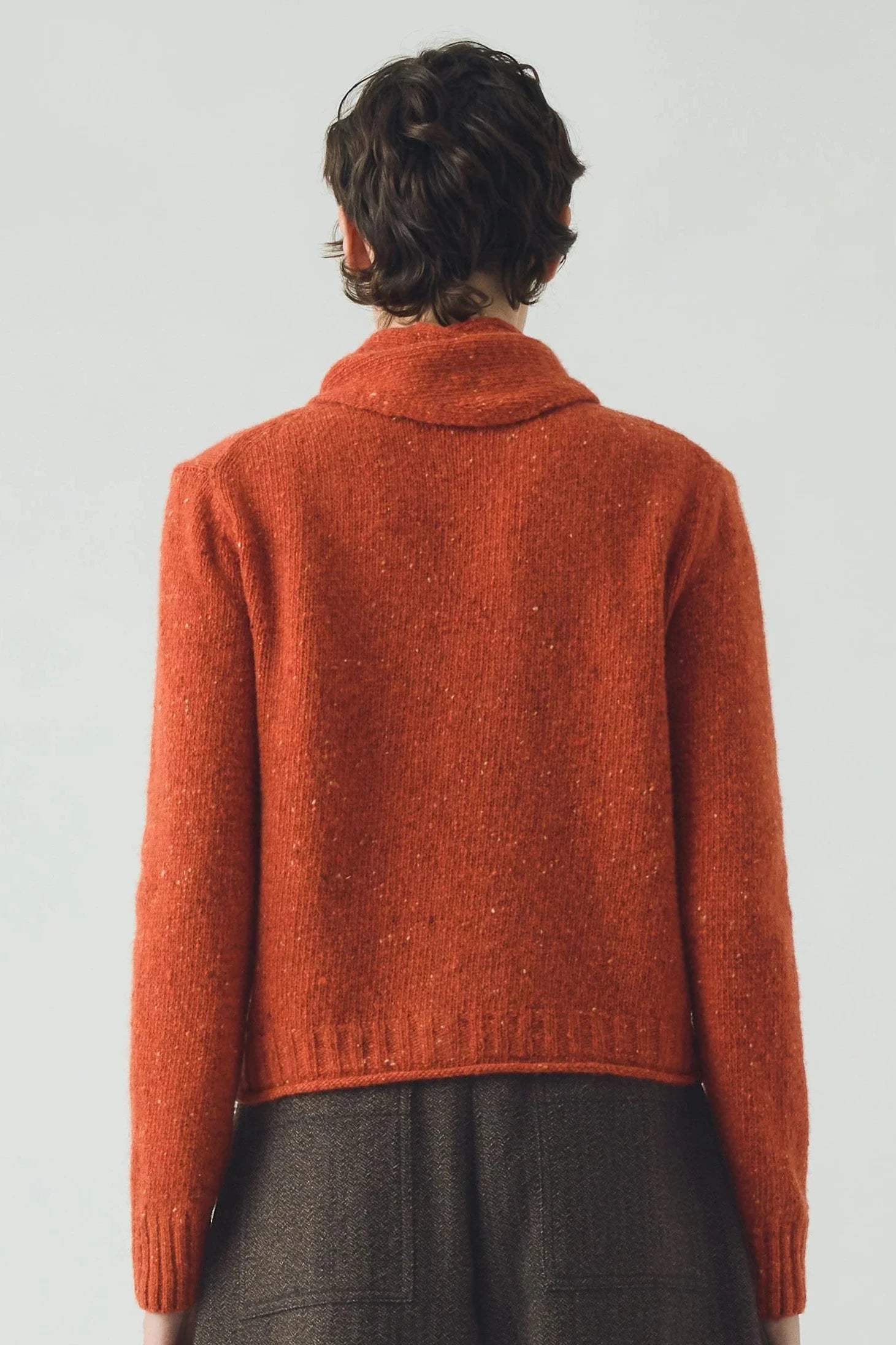 Person wearing a red knitted sweater on a plain background