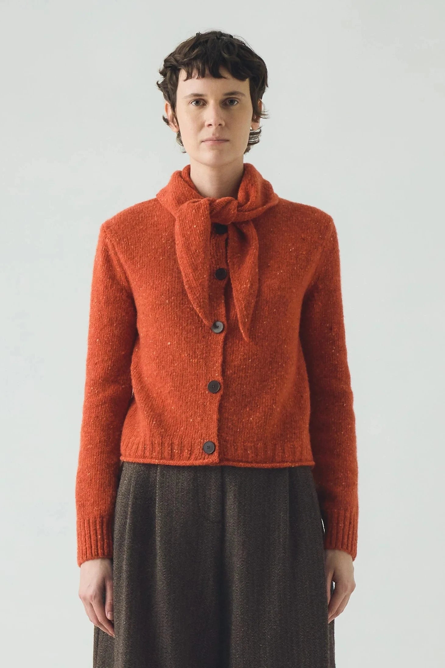 Person wearing an red  knitted cardigan with a white background