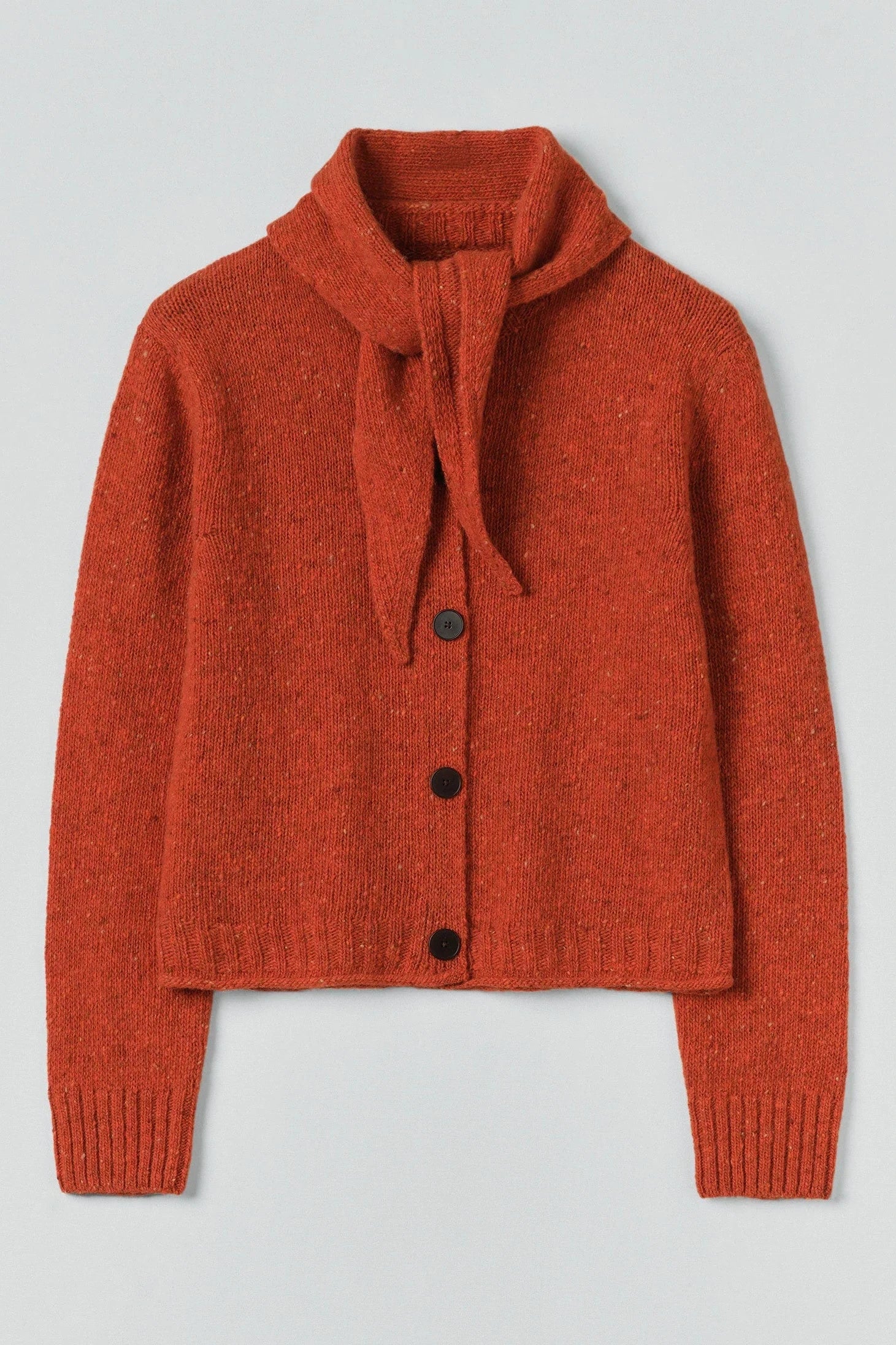 Red knitted cardigan with a tie collar on a light gray background