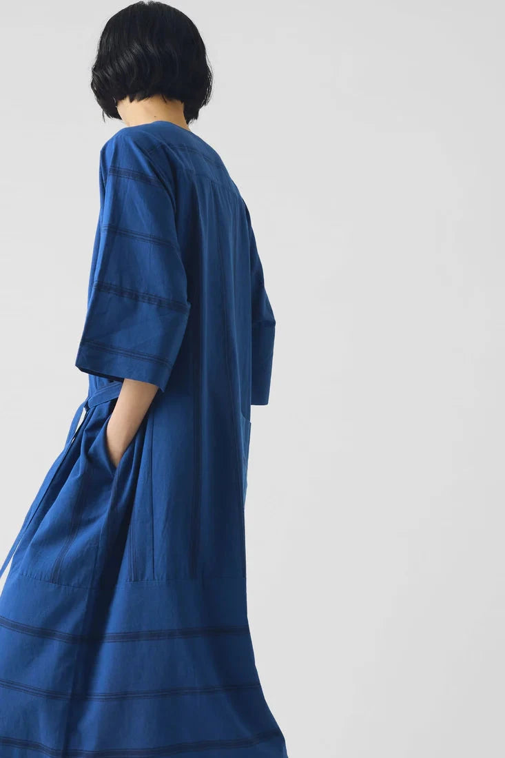 Person wearing a blue dress with a plain background