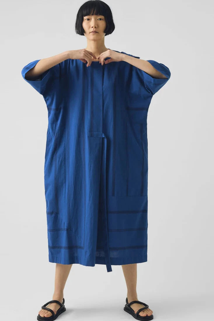 Person wearing a blue dress against a white background