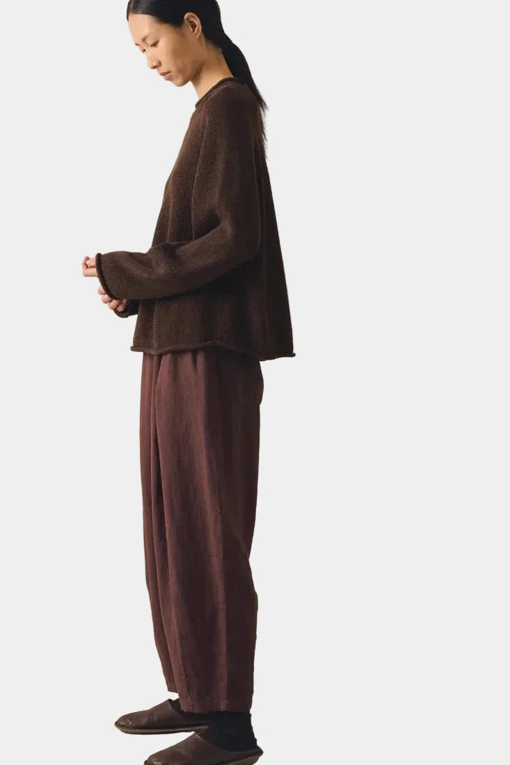 Person wearing a brown outfit standing against a plain background 