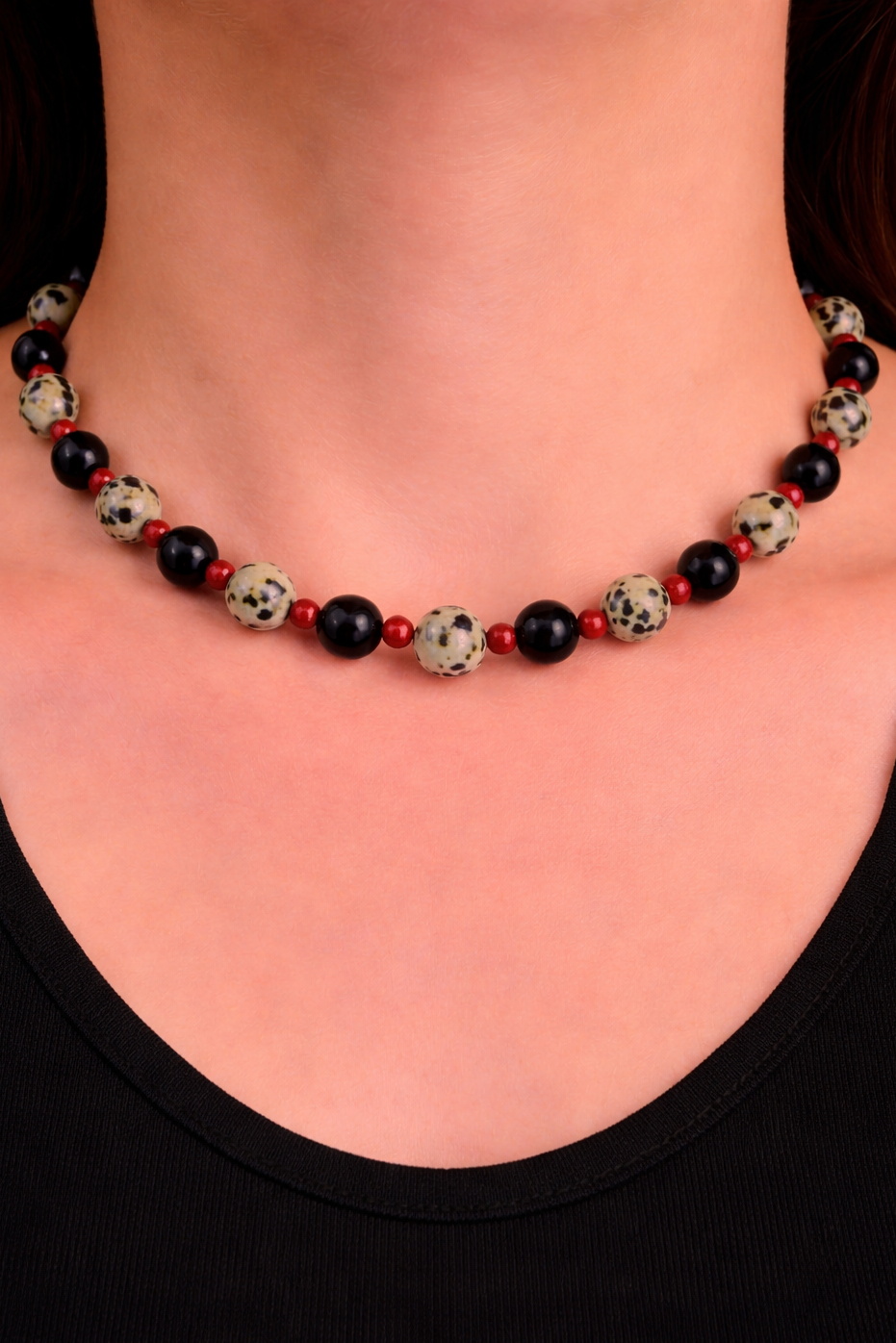 Necklace with black and red beads worn by a person against a black background