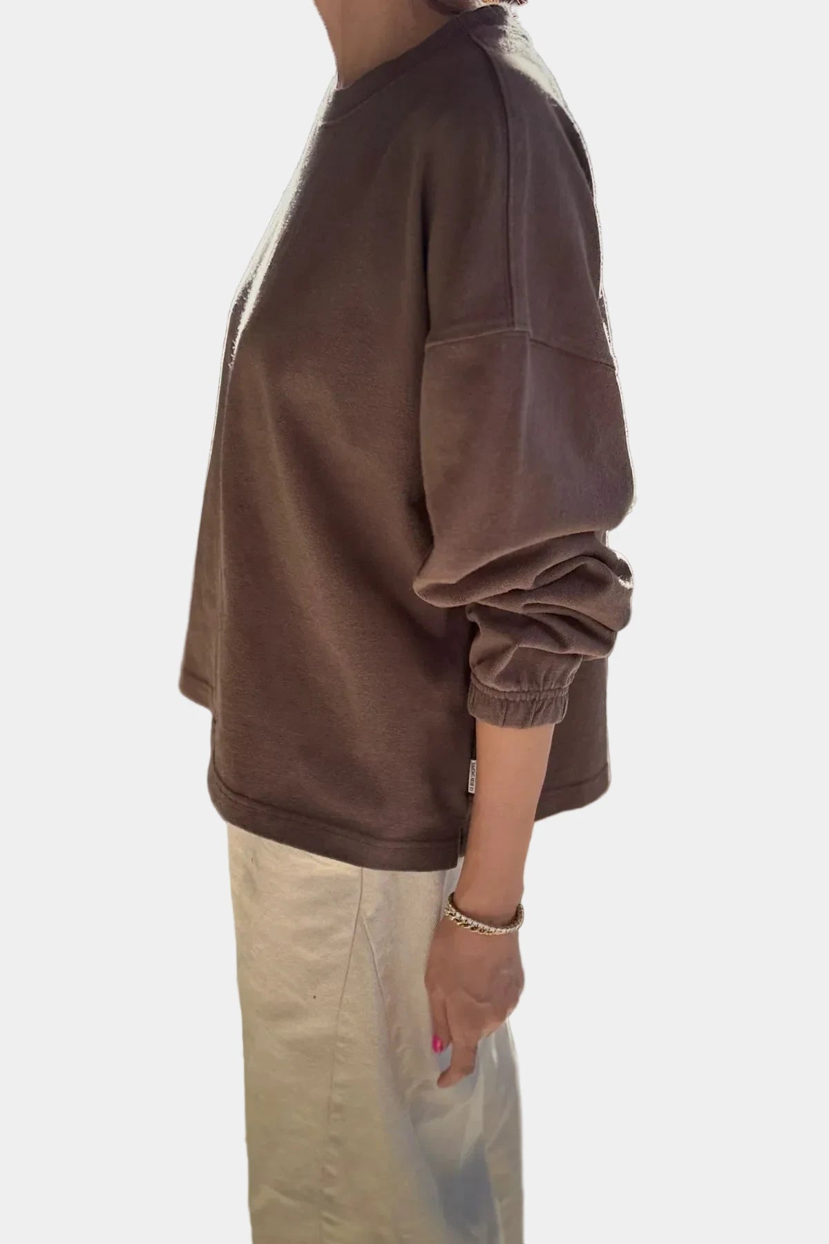 Person wearing a brown oversized sweatshirt against a plain background