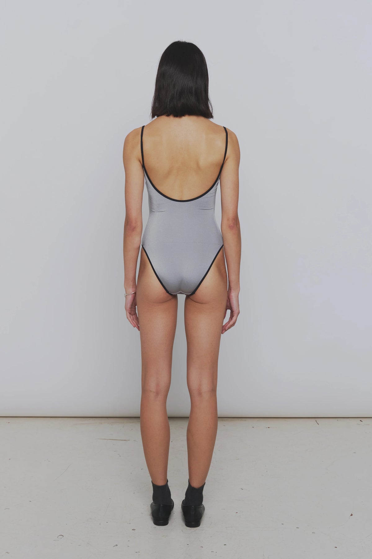 Rear View of a women wearing the Nu Swim Noodle one piece in silver - East Coast General
