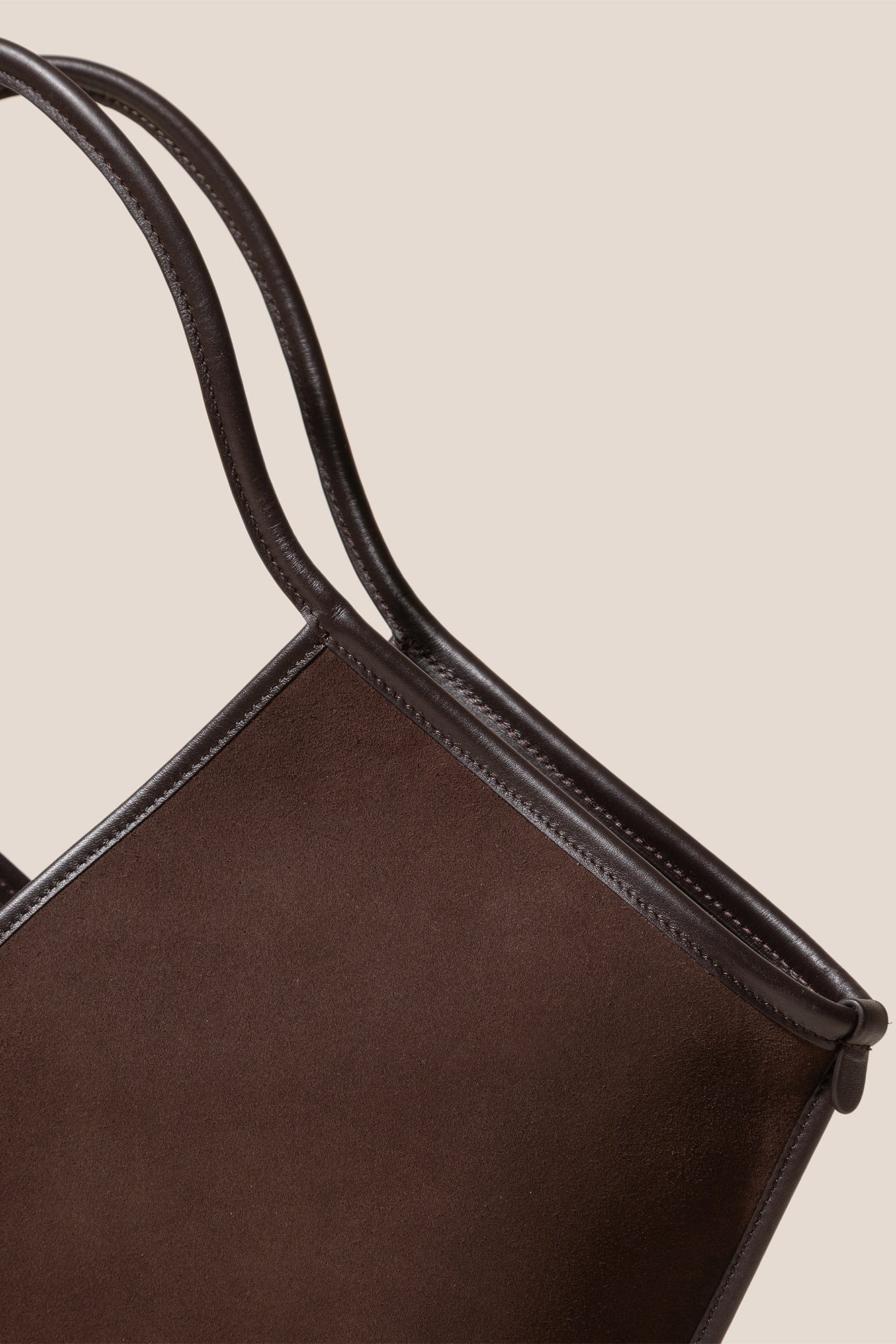 Brown leather tote bag with handles on a beige background