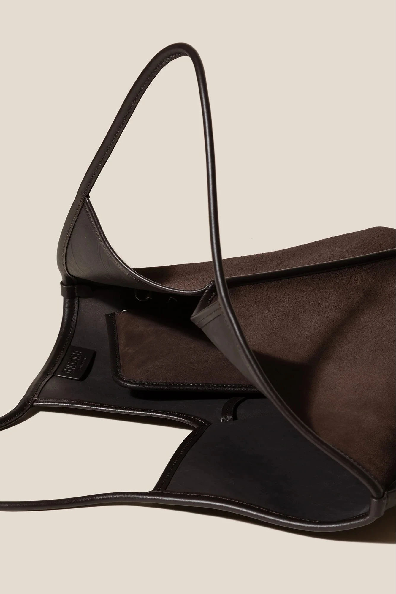 Brown leather bag with black straps on a beige background