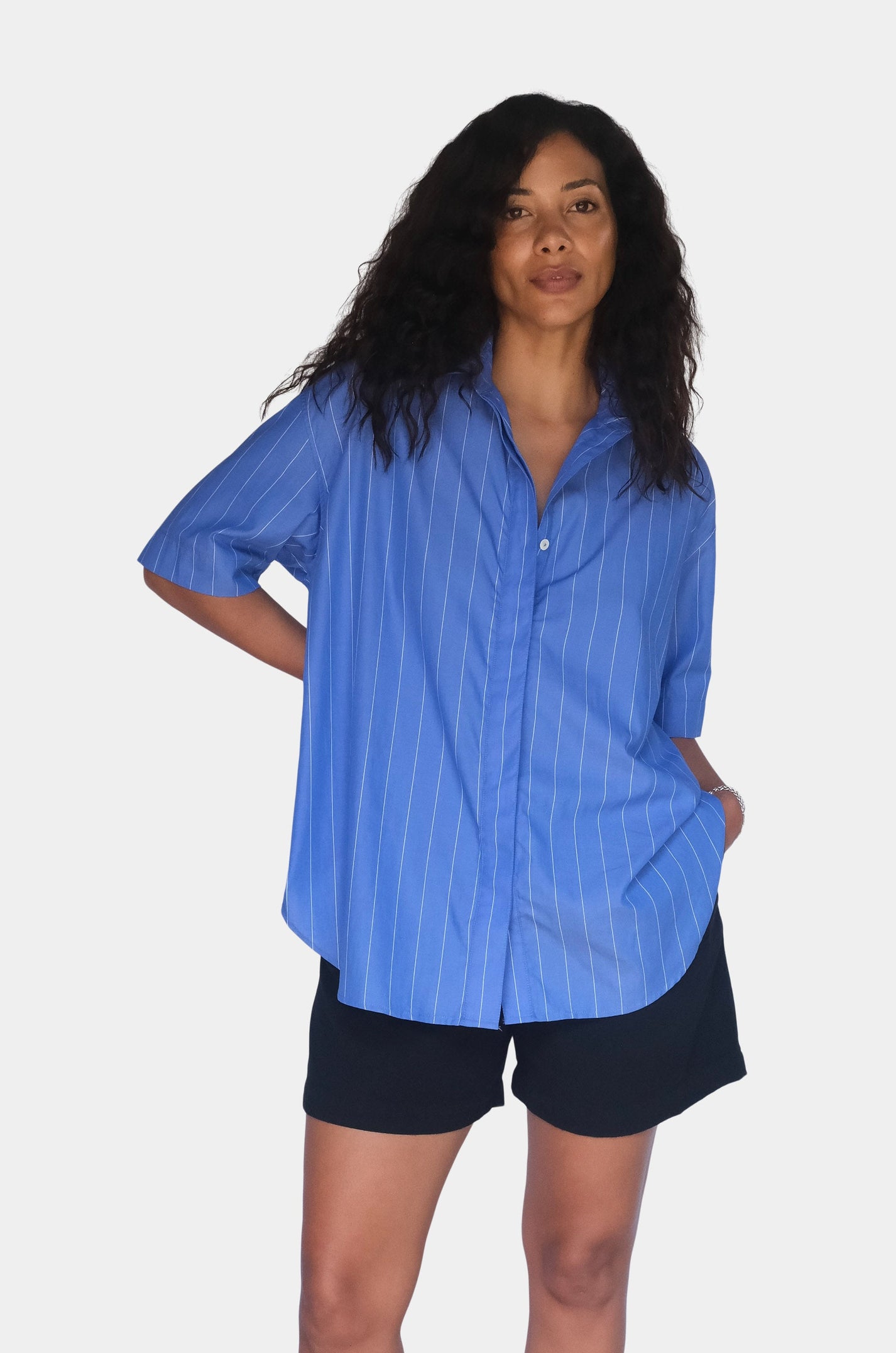 Woman wearing a blue shirt and black shorts on a white background