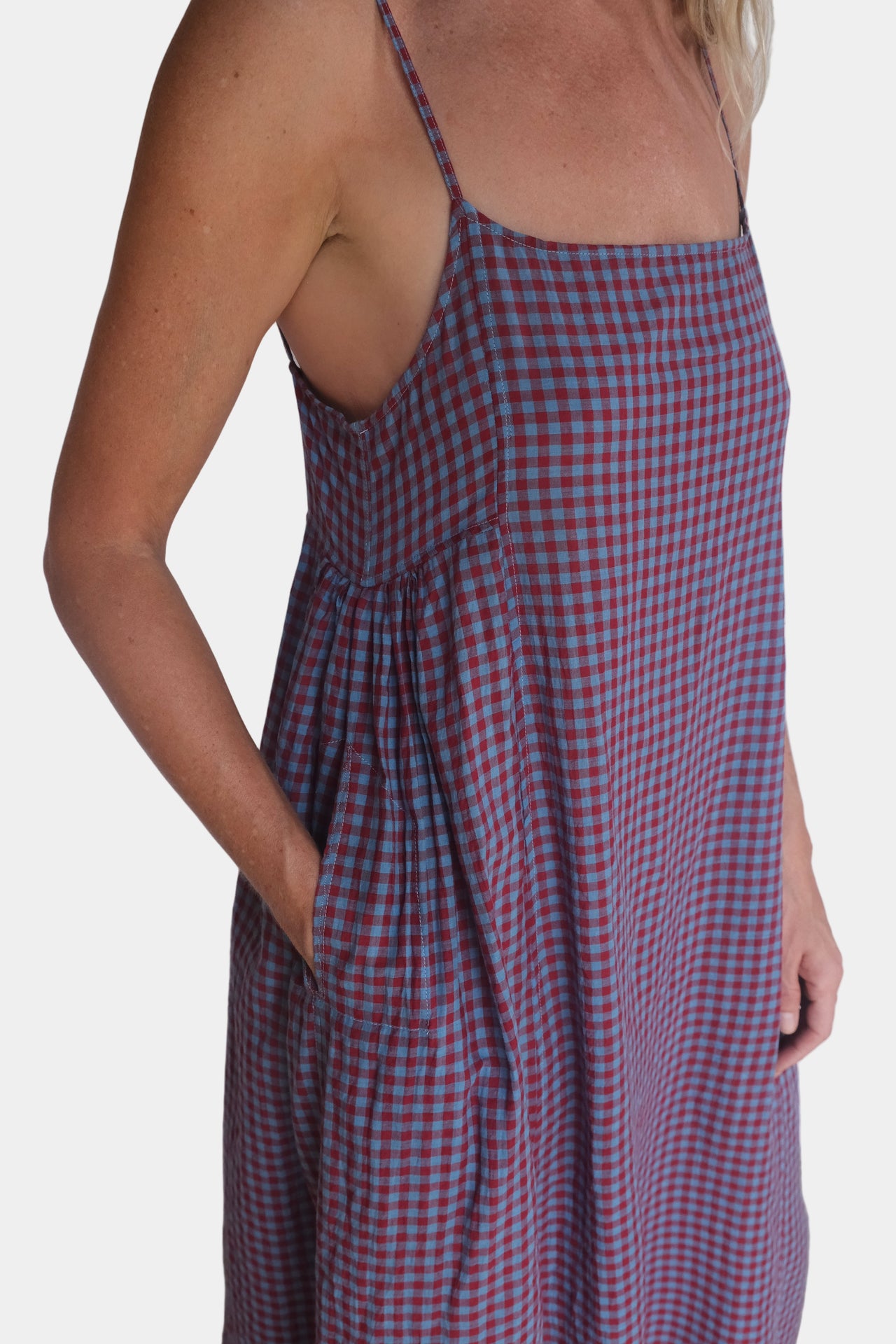 Person wearing a red and blue checkered dress against a white background