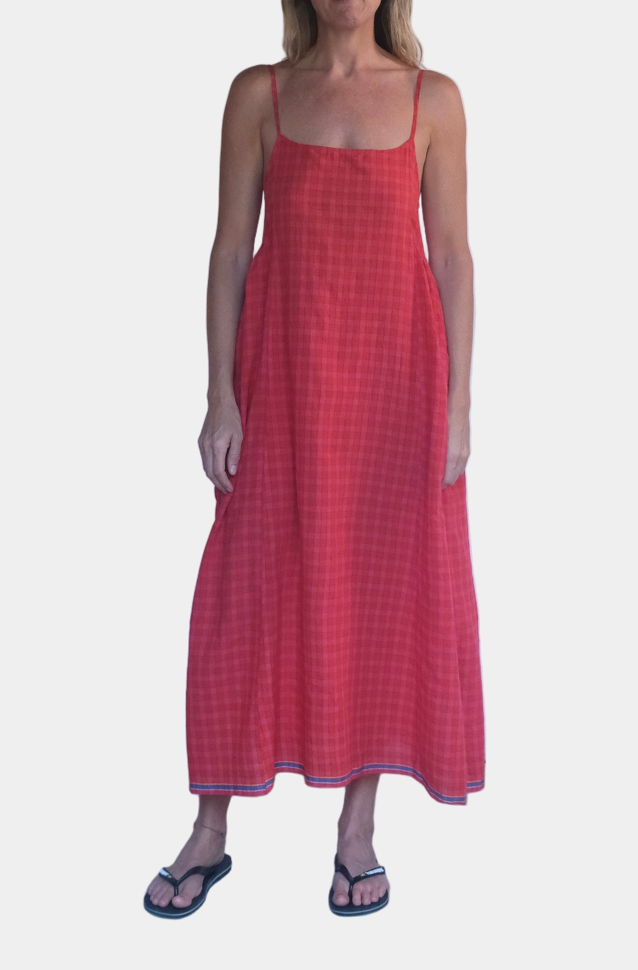 Woman wearing a red dress standing against a white wall.