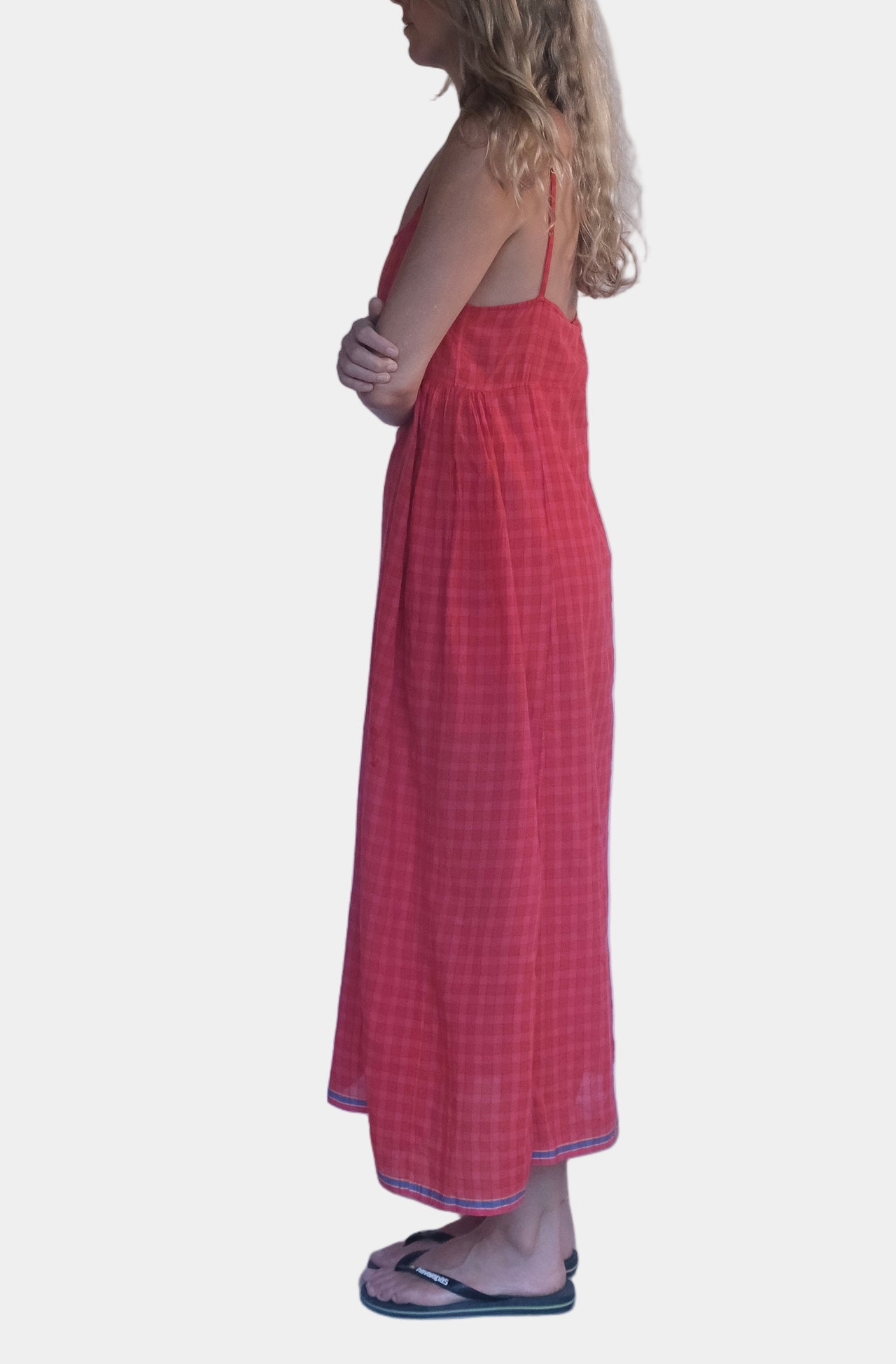 Woman wearing a red dress standing against a white wall.