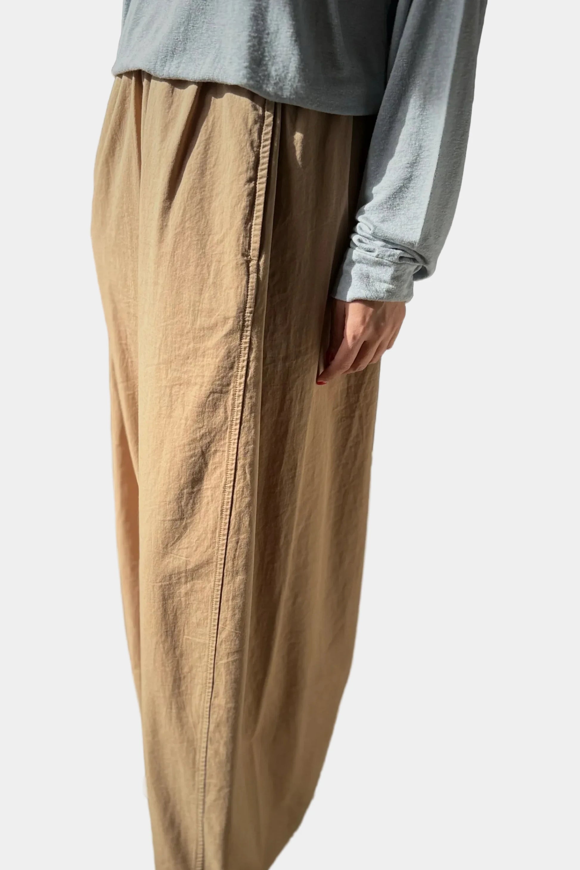 Person wearing beige pants and a light blue shirt against a plain background 