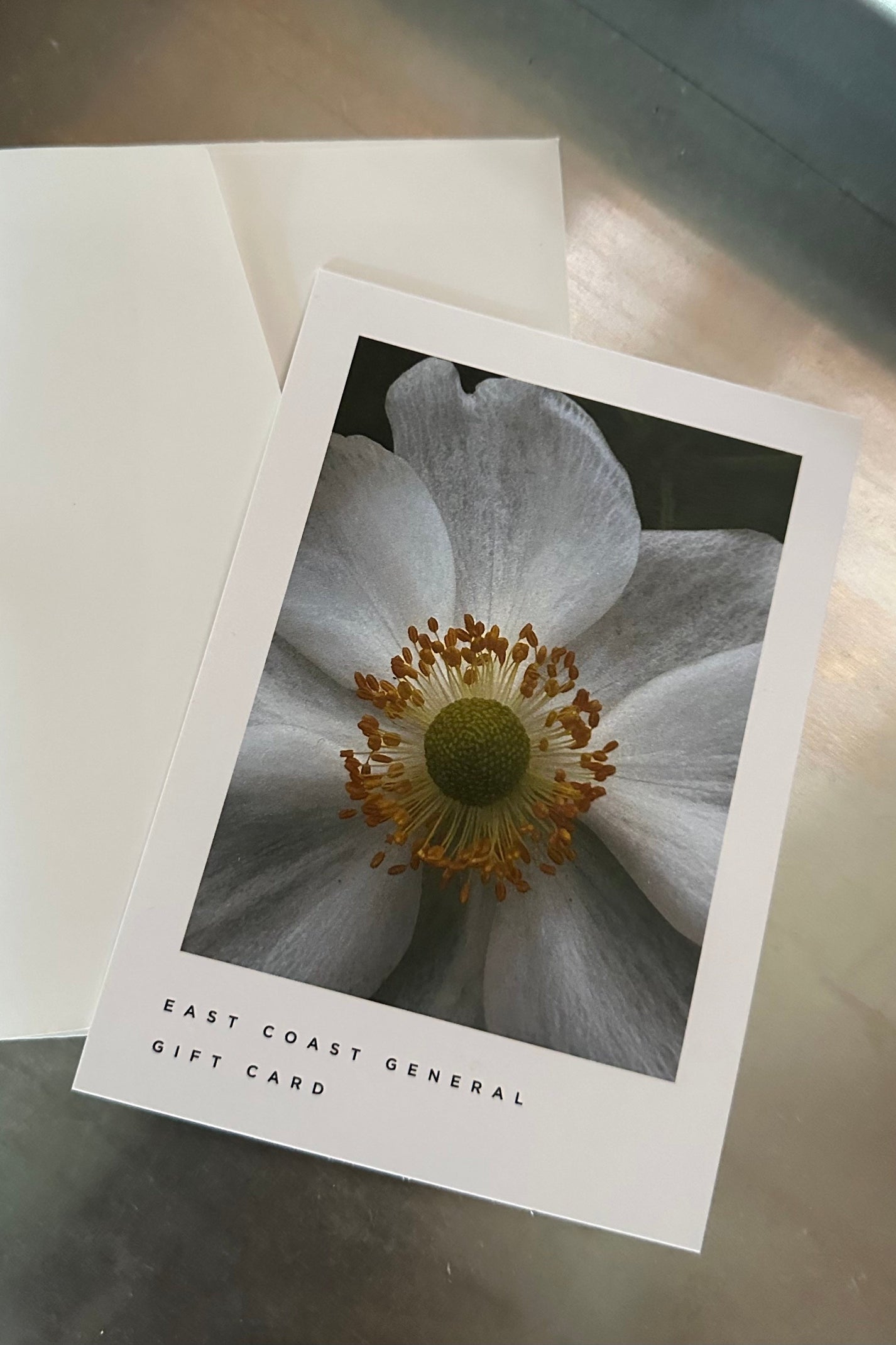 A physical gift card with an envelope, featuring a close-up photograph of a flower on the front.