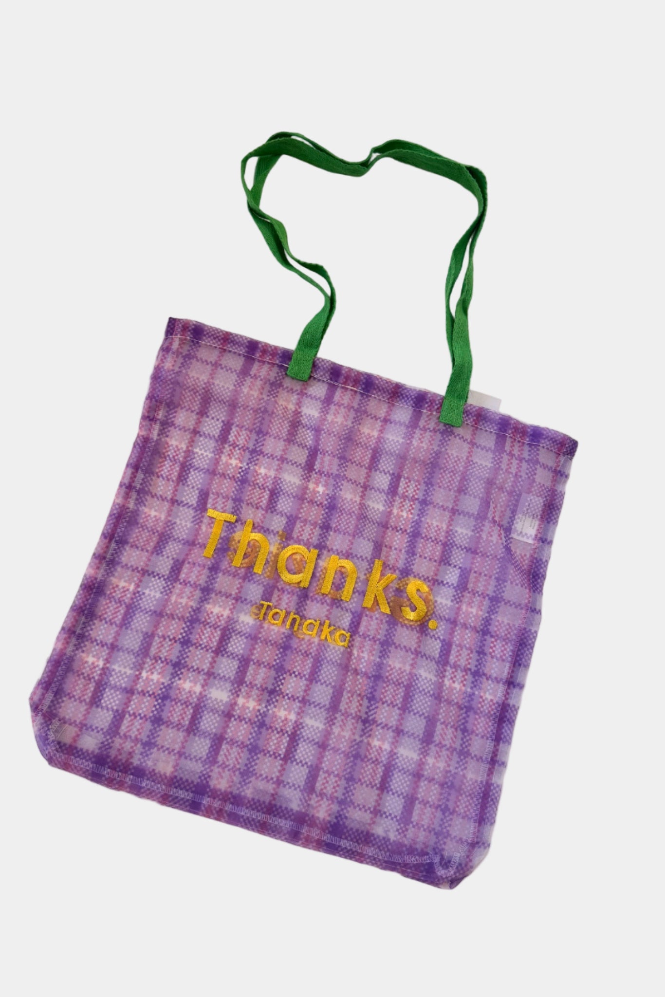 Purple plaid tote bag with green handle and 'Thanks Tanaka' text on a white surface
