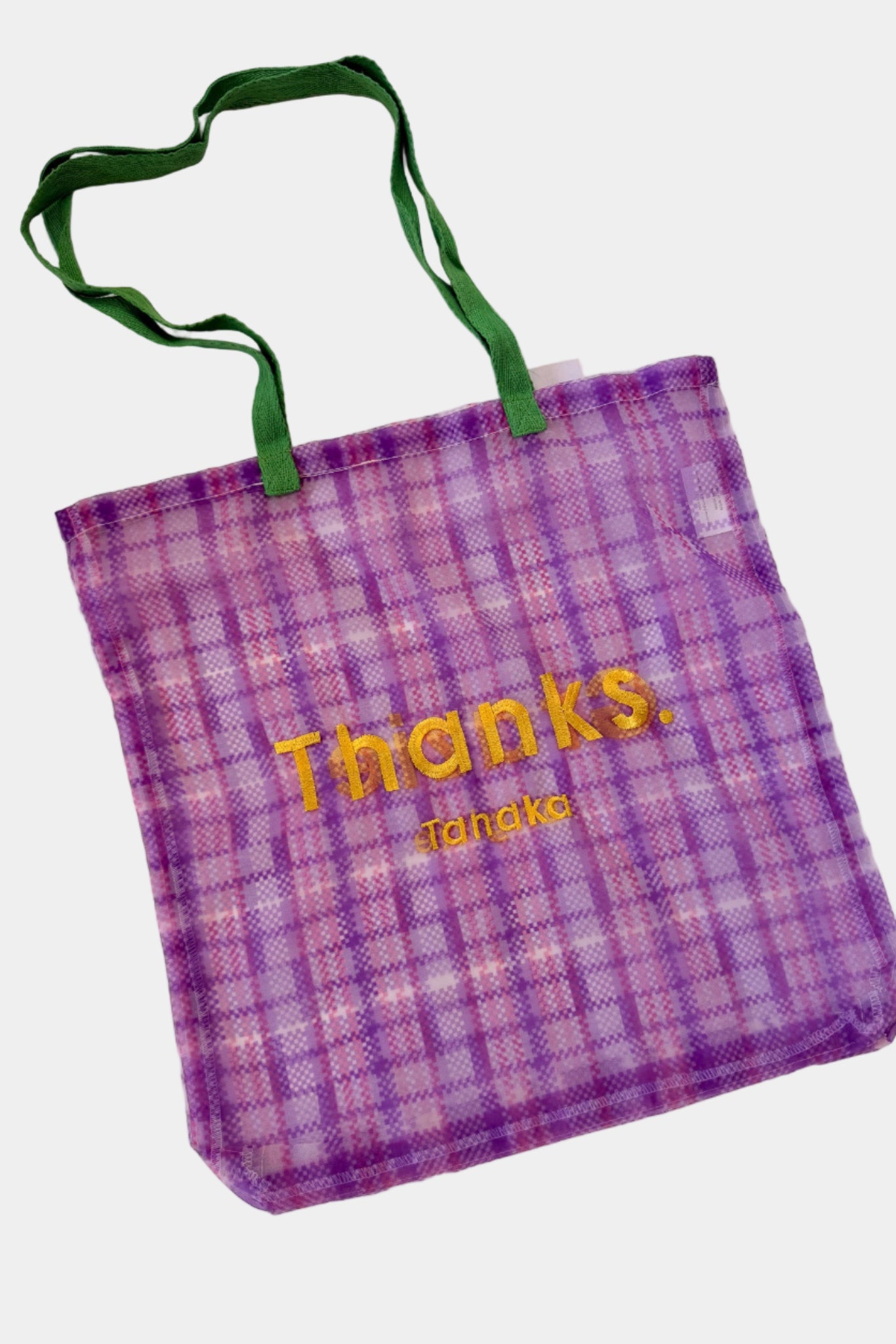 Purple plaid tote bag with green handles and yellow text on a white background