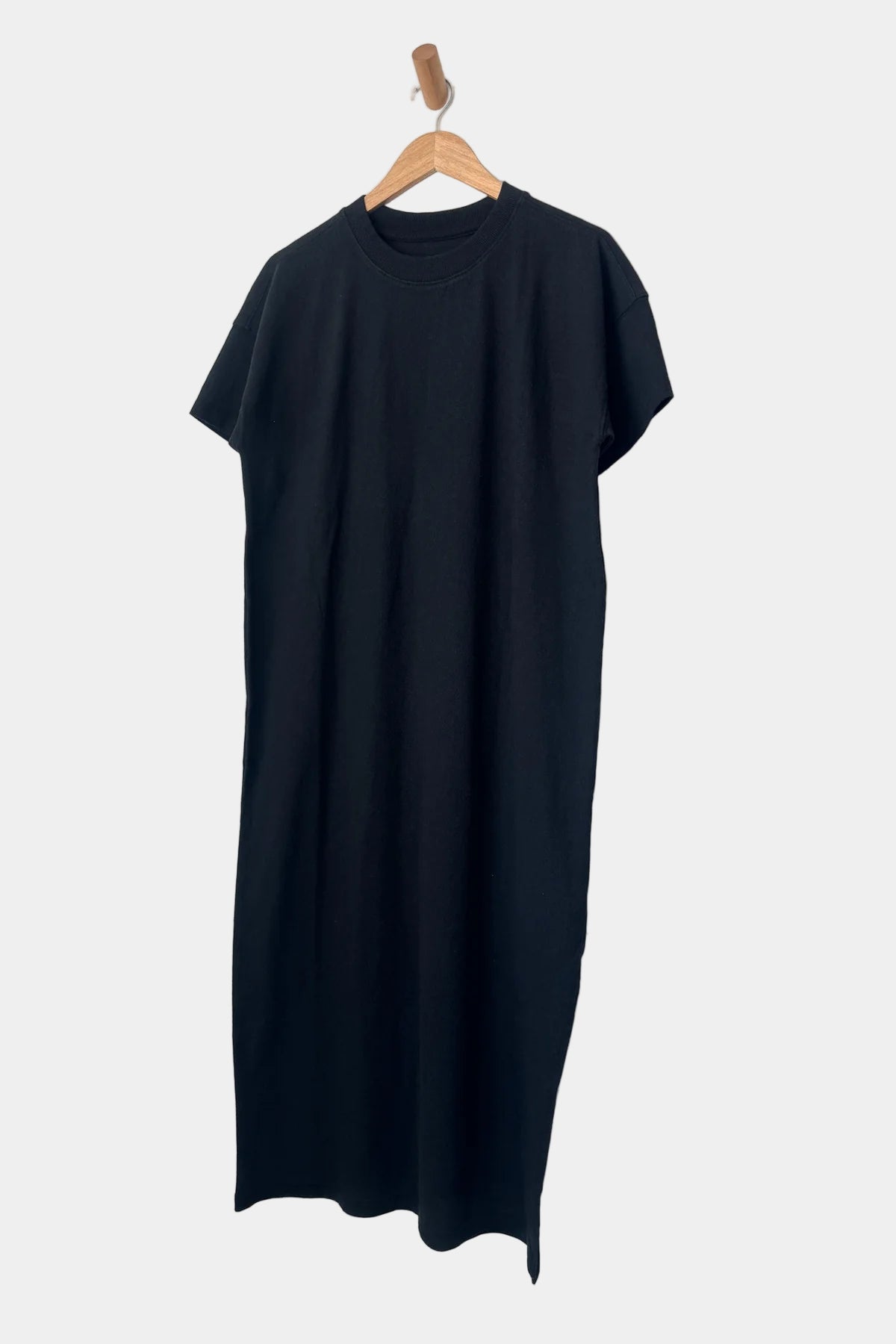 Person wearing a black dress with a slit and light blue shoes ahainst a white background.