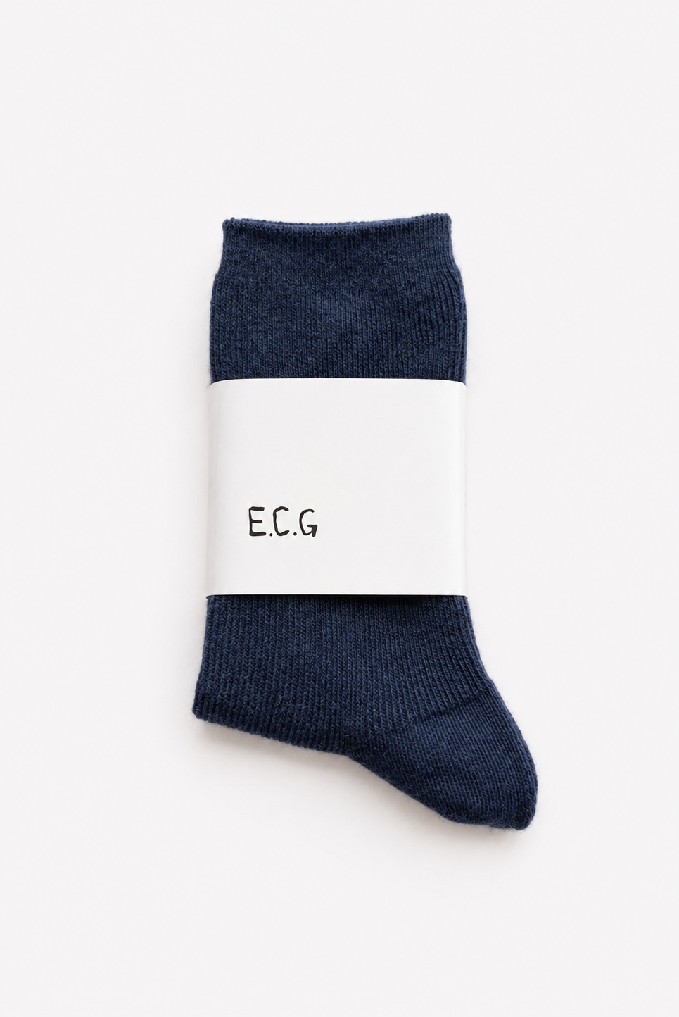A pair of ink blue cotton ribbed crew socks wrapped in a white paper band with the letters 'E.C.G’ - East Coast General