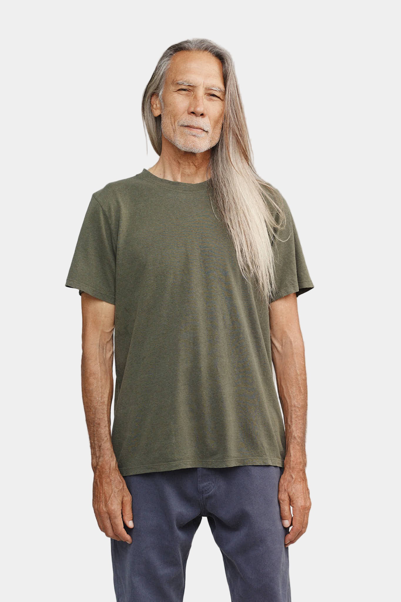 Man wearing a green t-shirt and blue pants against a plain background