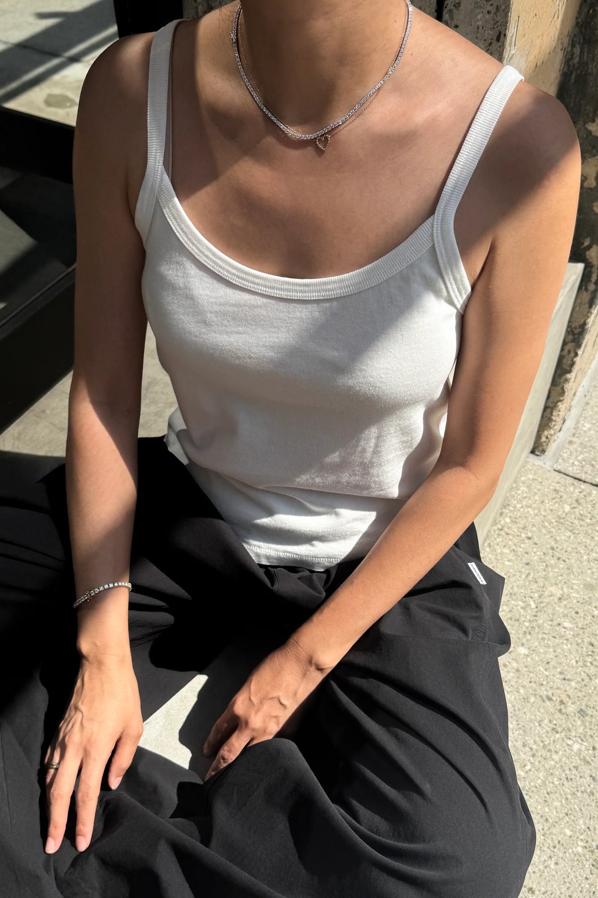 Seated detail shot of model wearing Le Bon Shoppe Premium Jersey Dana Cami in Vintage White showing scoop neck