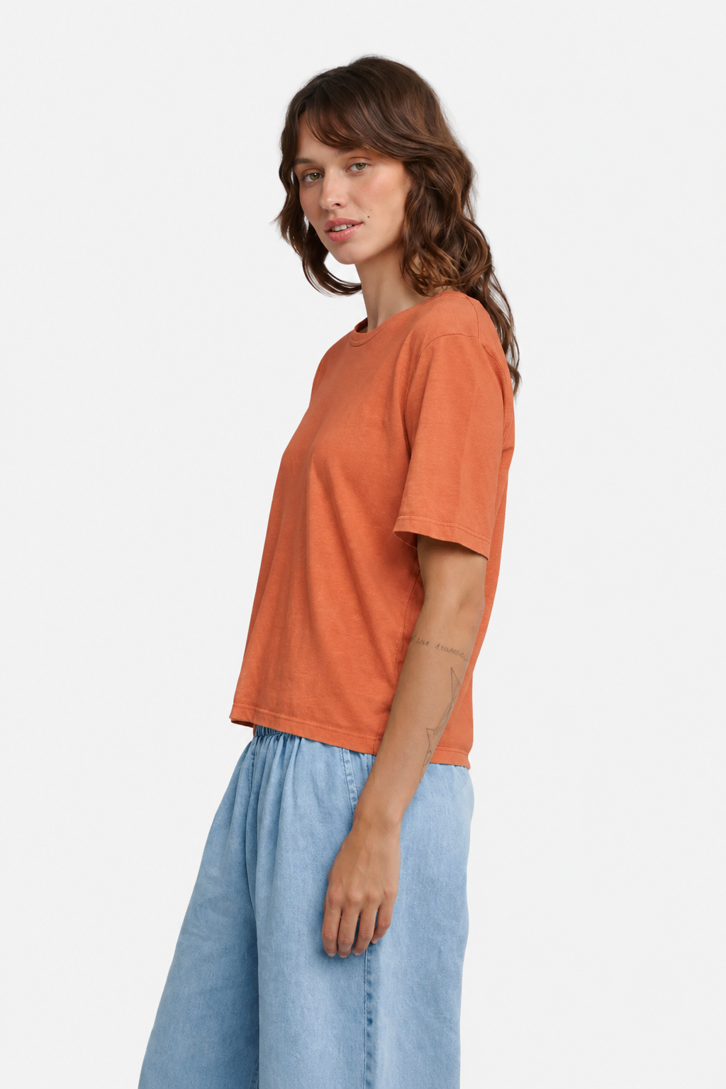 A person wearing Jungmaven Silverlake Tee in Pumpkin Spice, side view - East Coast General