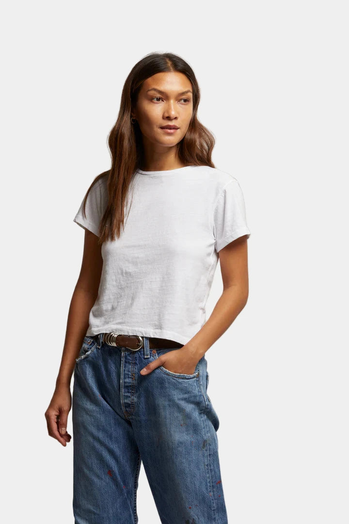 Woman wearing a white t-shirt and blue jeans against a plain background
