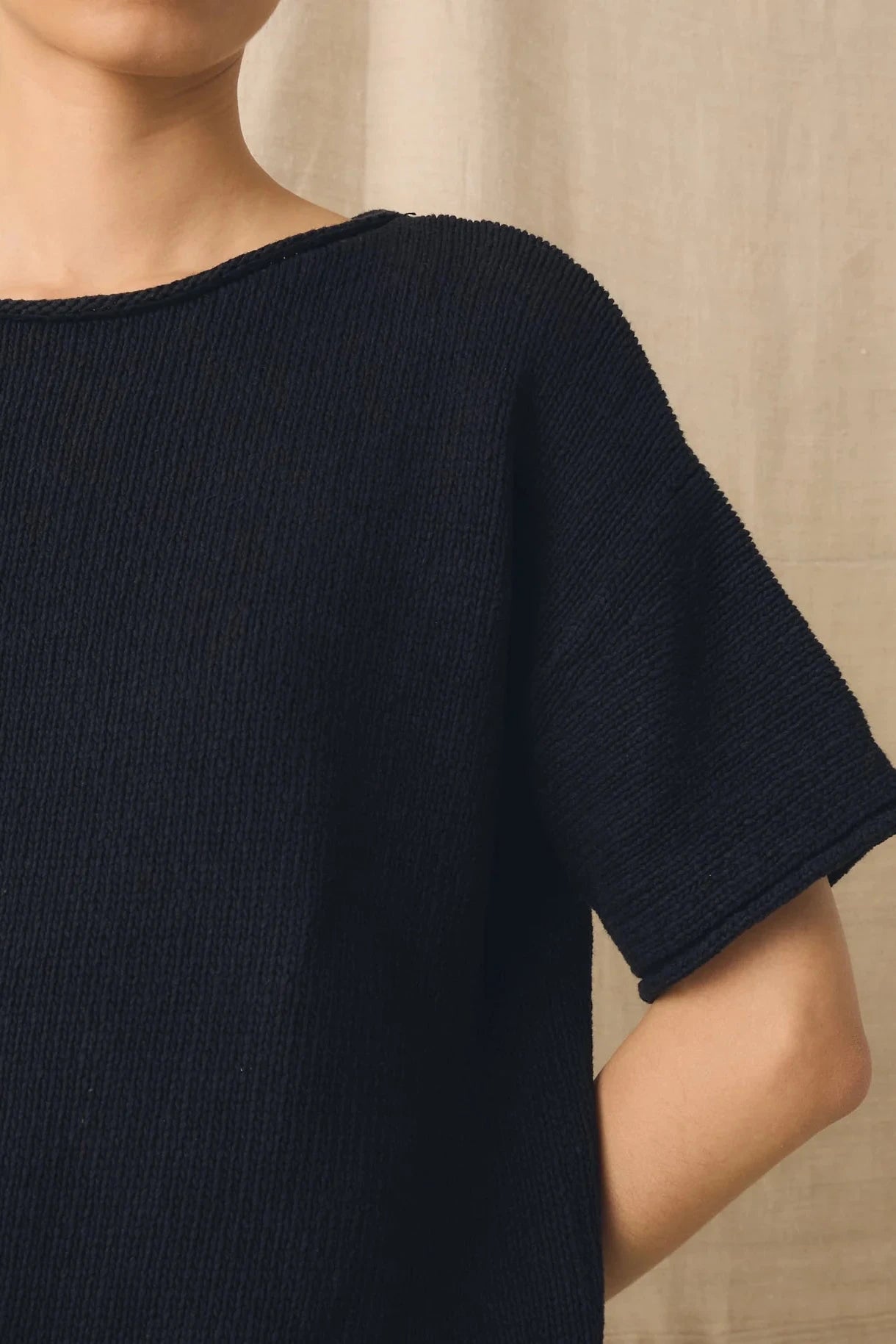 Navy blue short-sleeve top worn by a person against a neutral background