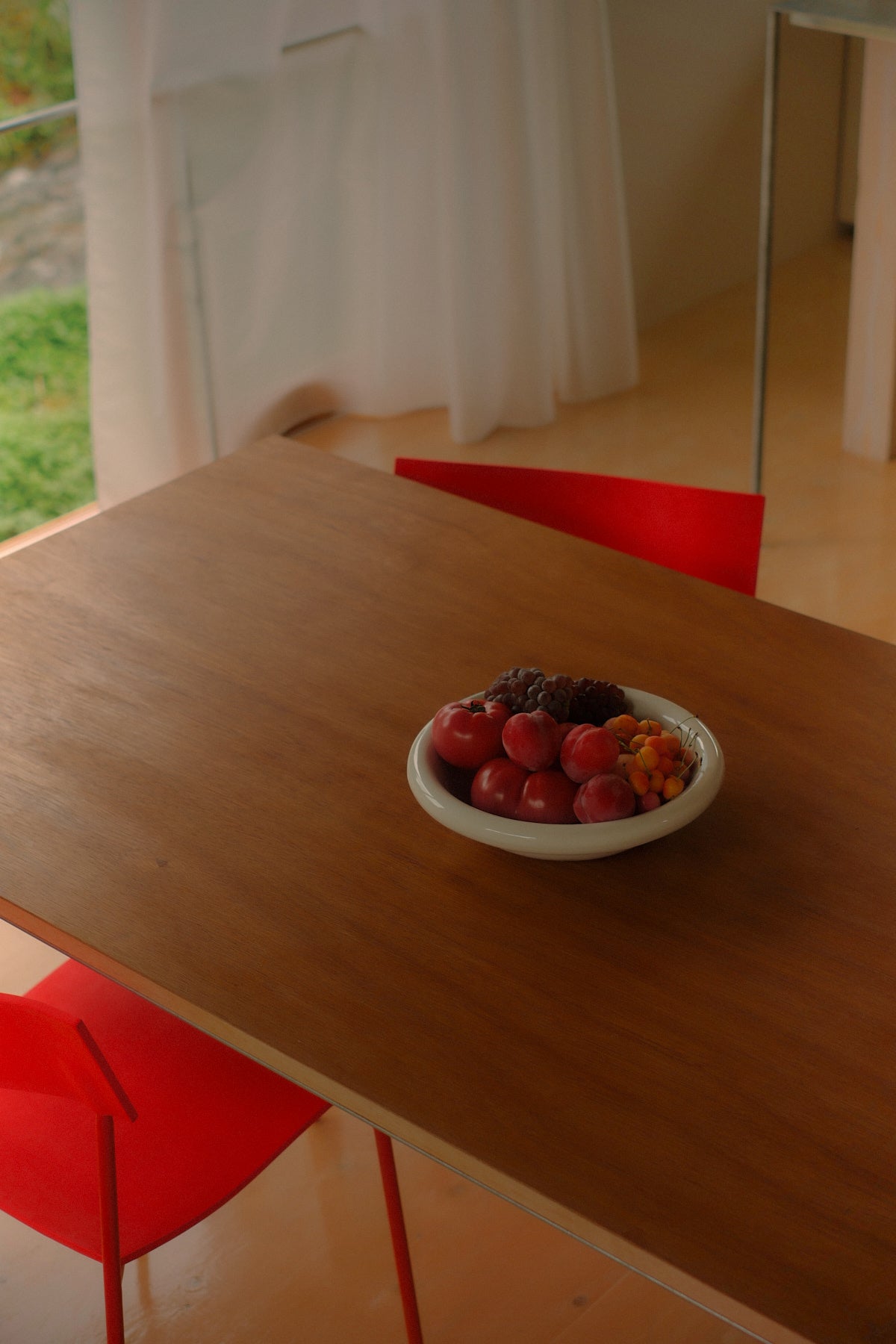 softedge serving bowl in marshmellow filled with fruit sitting on a wooden table with red chairs
