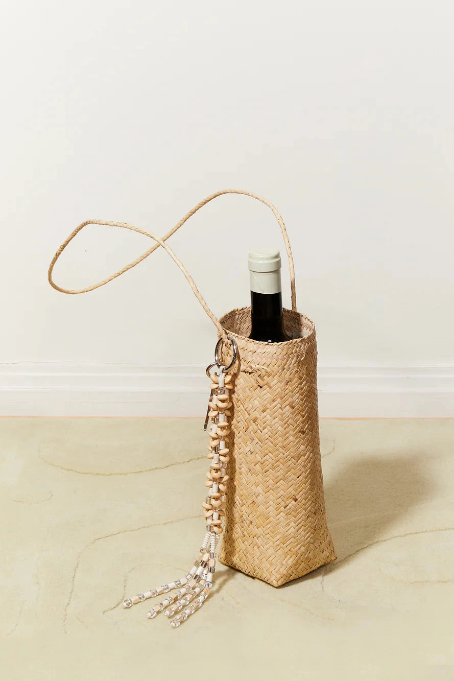 Woven straw bottle holder with a bottle of wine on a light background