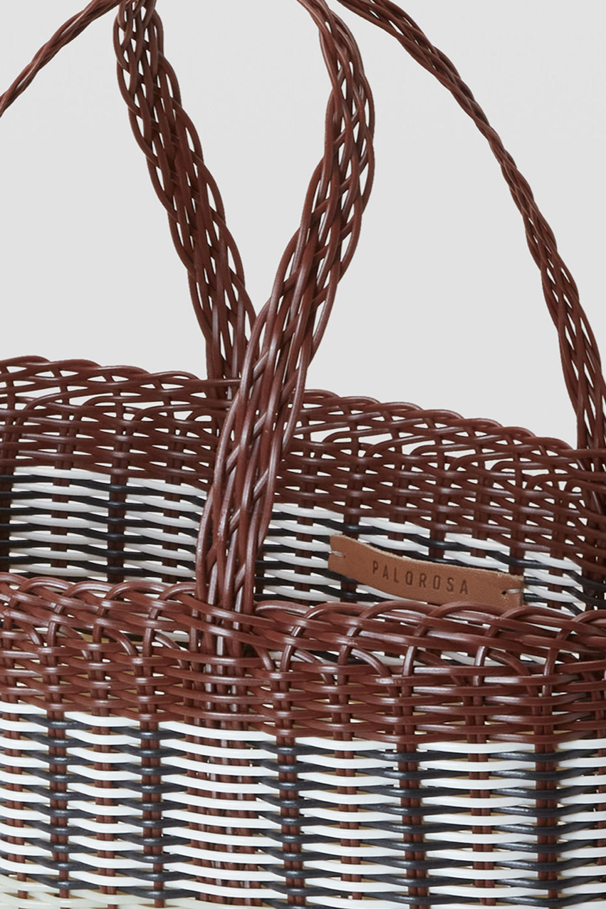 Plastic woven basket with handles and visible brand name on a light gray background